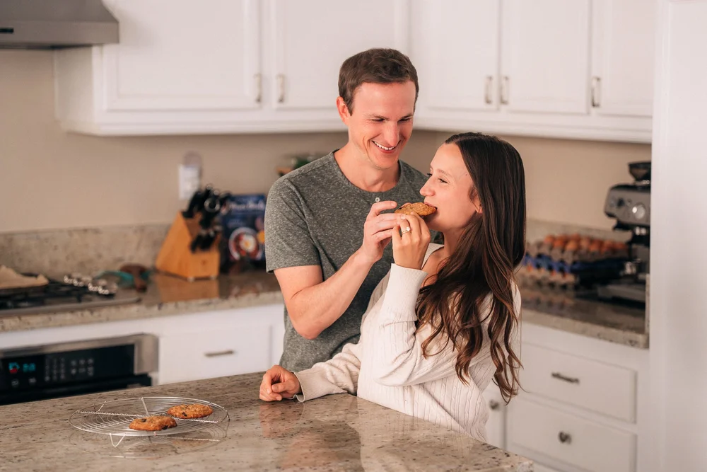 Dad feeding mom a bite of cookie, both laughing