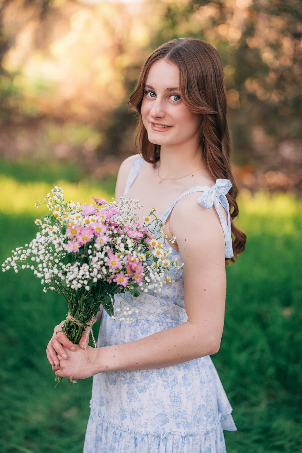 Emily holding a wildflower bouquet in soft sunset light, Coto de Caza senior session