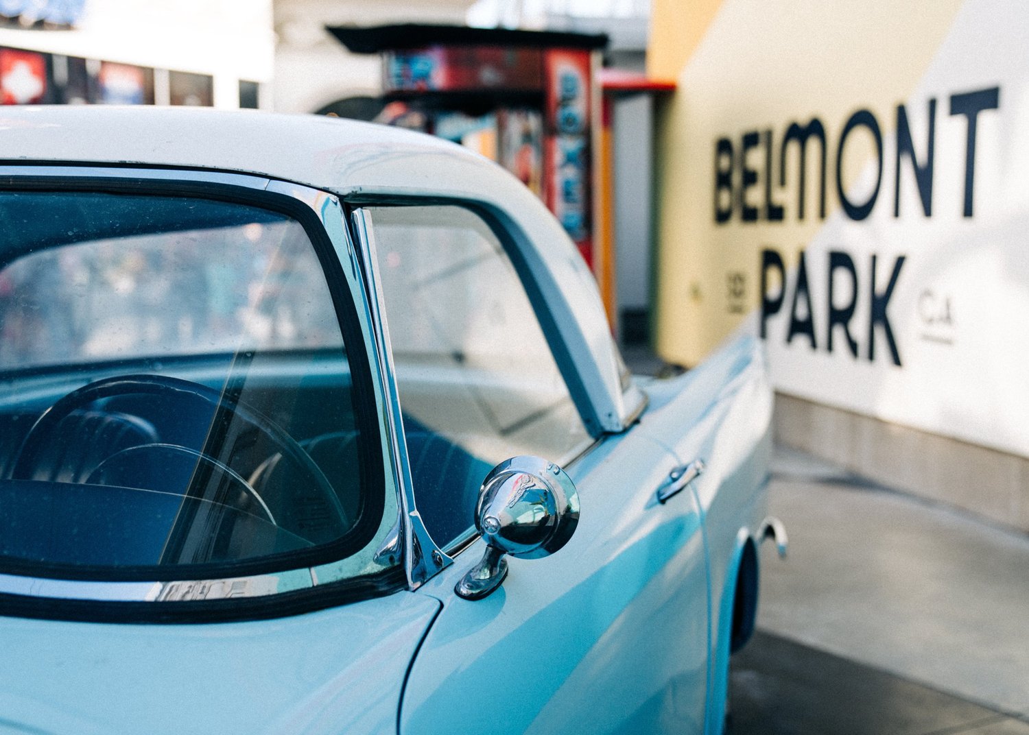 Detail of a vintage powder blue classic car parked beneath the Belmont Park sign, San Diego