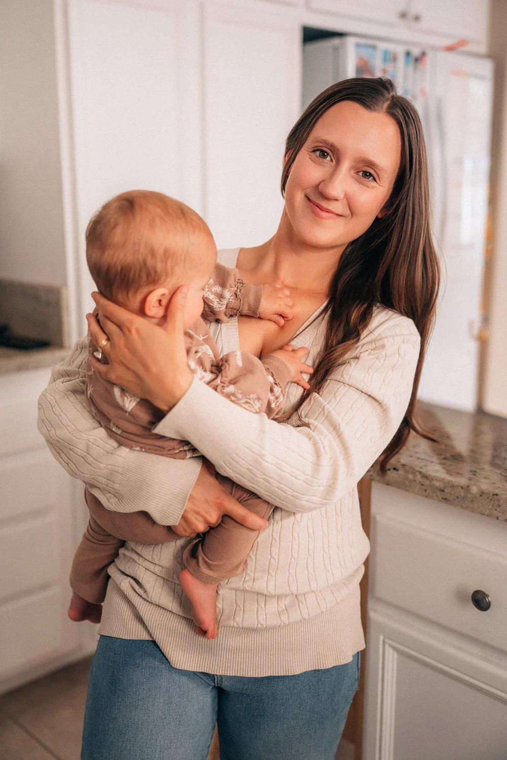Mom holding her baby close, smiling softly at the camera