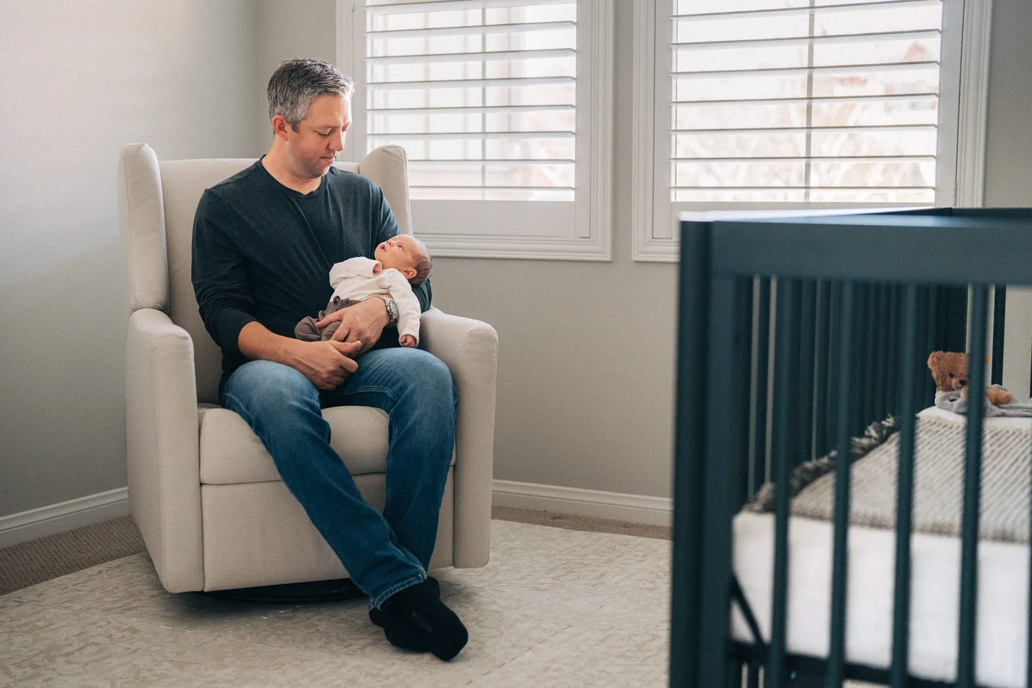 Dad in nursery glider chair holding newborn, Hunter family in-home session Rancho Mission Viejo