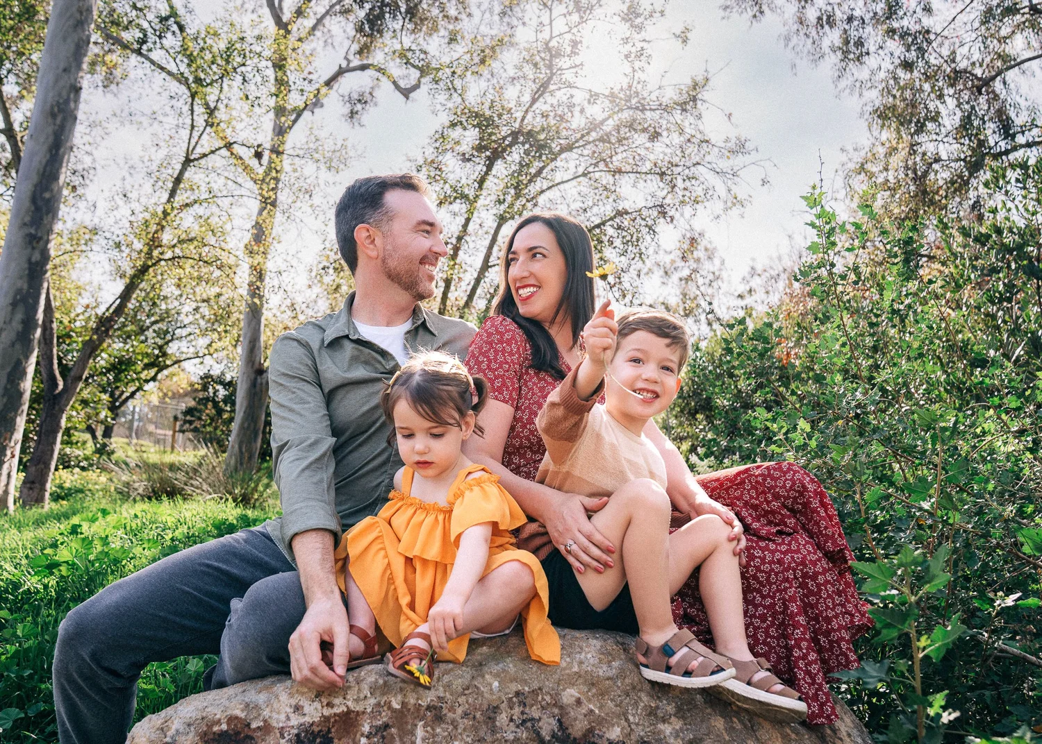 The Leon family seated together on a rock among the trees