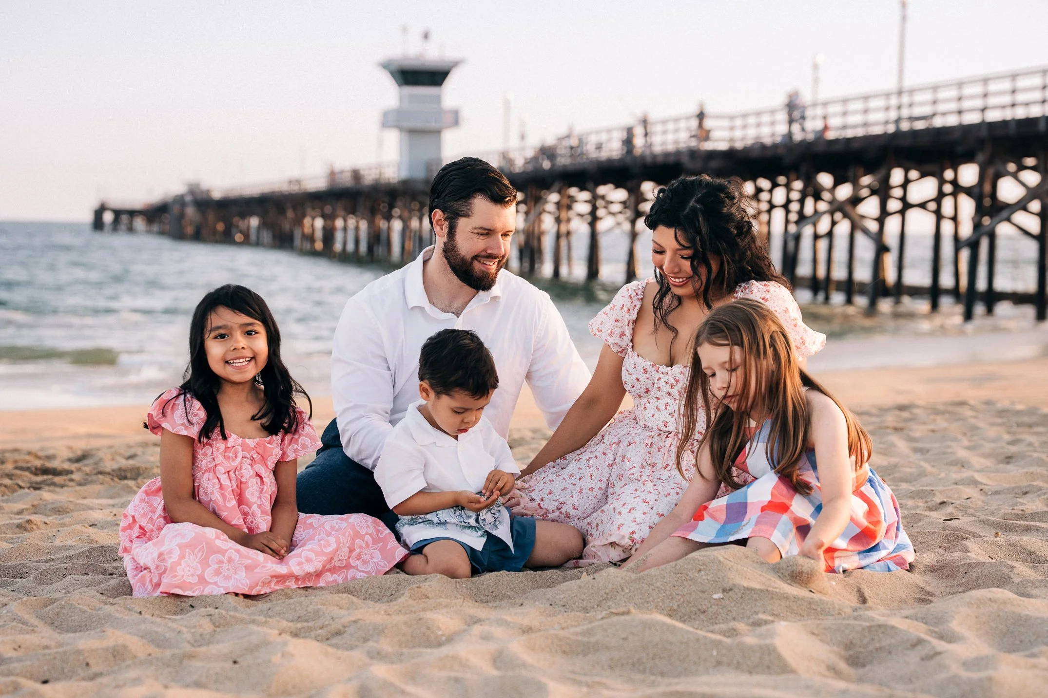 Family photo session on the wide sand near the wooden Seal Beach Pier