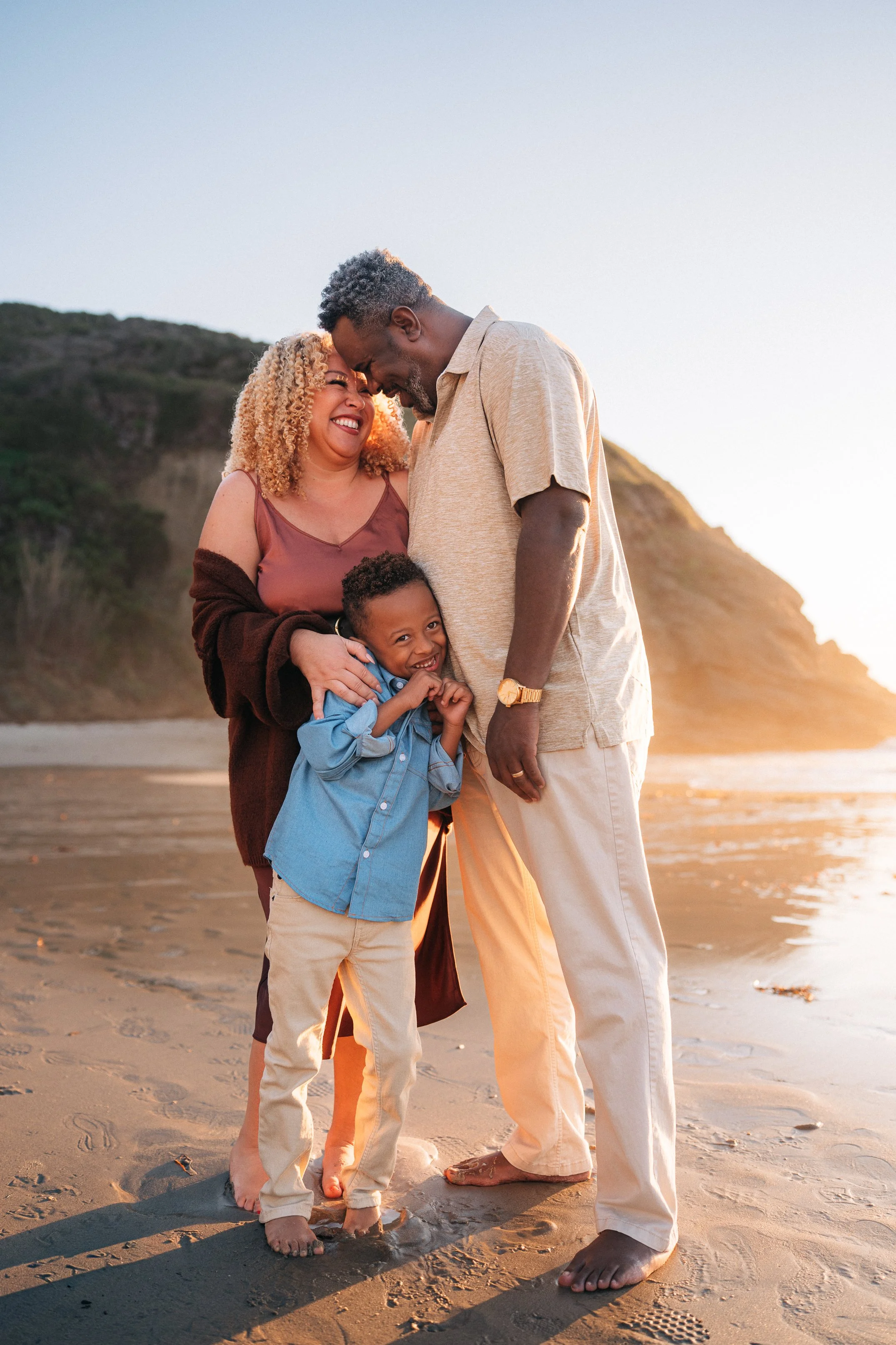The McDaniel family standing together at sunset, parents nuzzling above their son