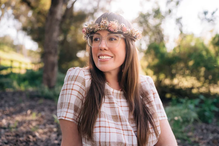 A woman with a floral crown smiling on a sunny oak-lined trail at Oak Canyon Nature Center
