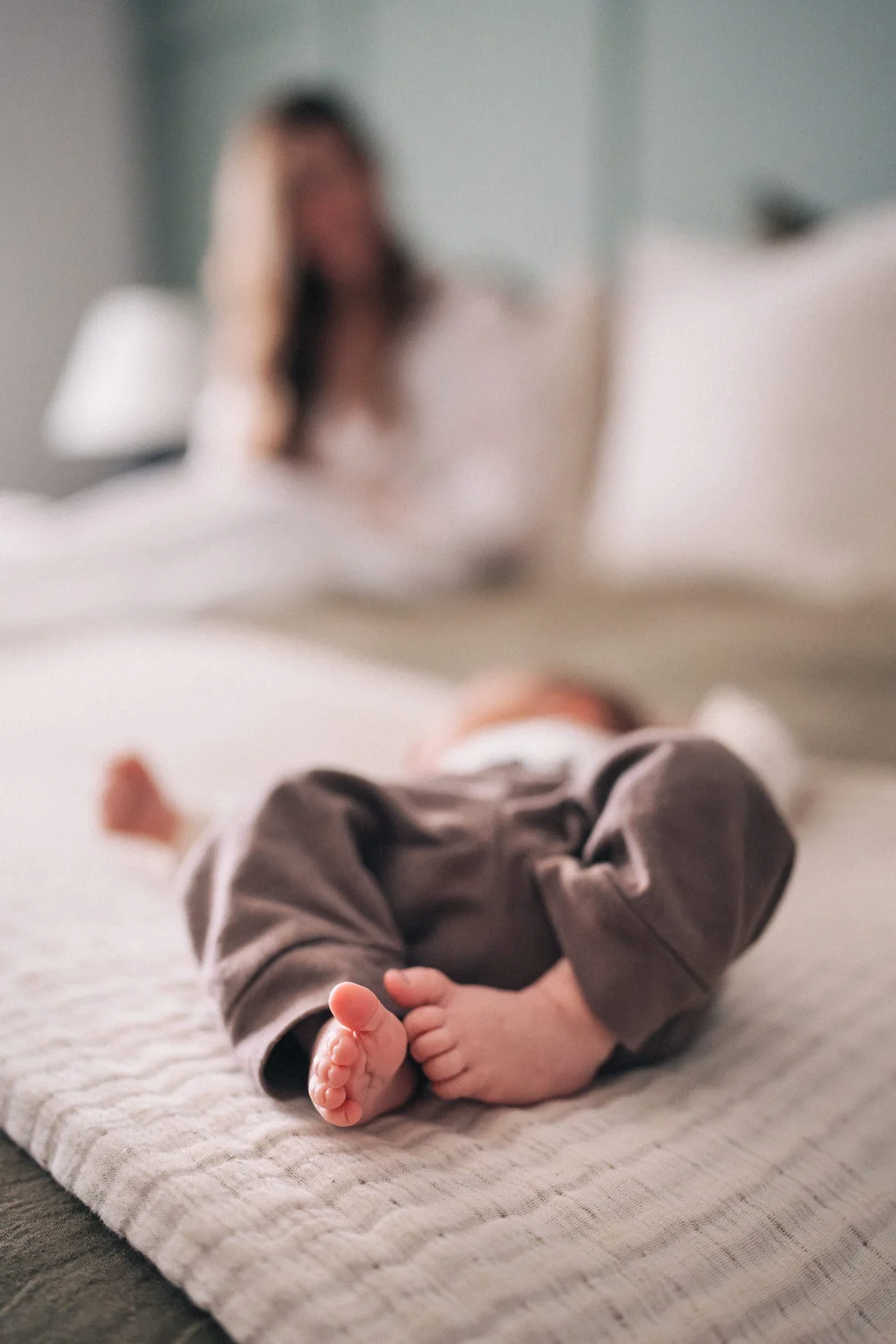 Newborn lying on the bed with mom in the background, Hunter family in-home session Rancho Mission Viejo