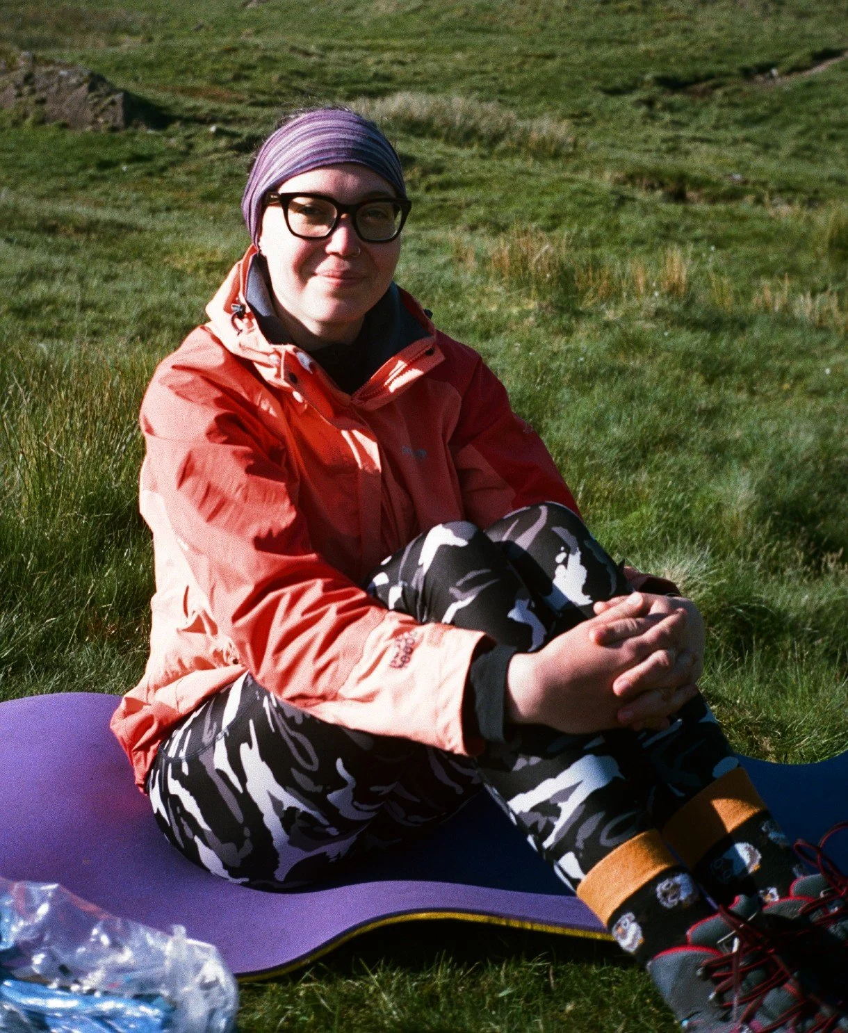 A 35mm film portrait of a woman wearing hiking clothing sits on a camping mat in the Lake District. Guiding services and mountain leader in the UK.