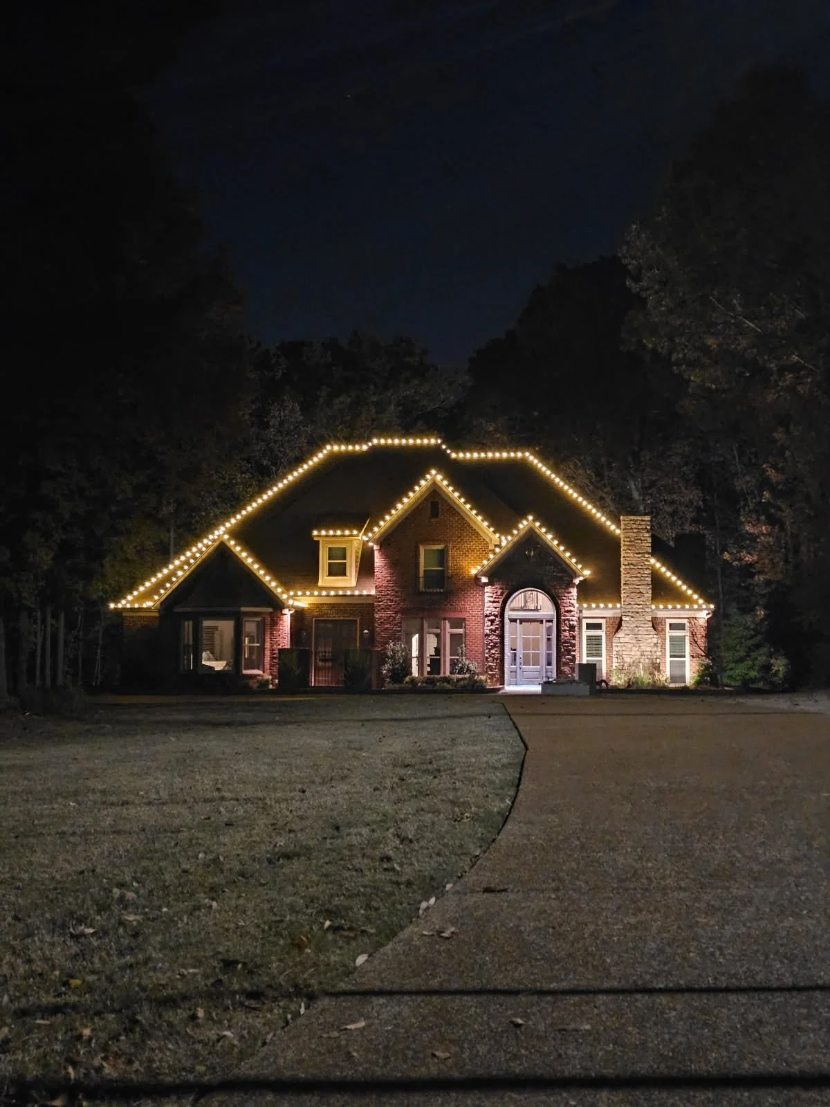 Ranch home lit with warm white Christmas lights along every roofline