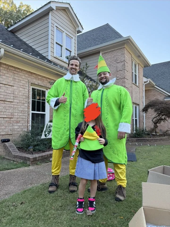 Two elf crew members posing with a happy young customer