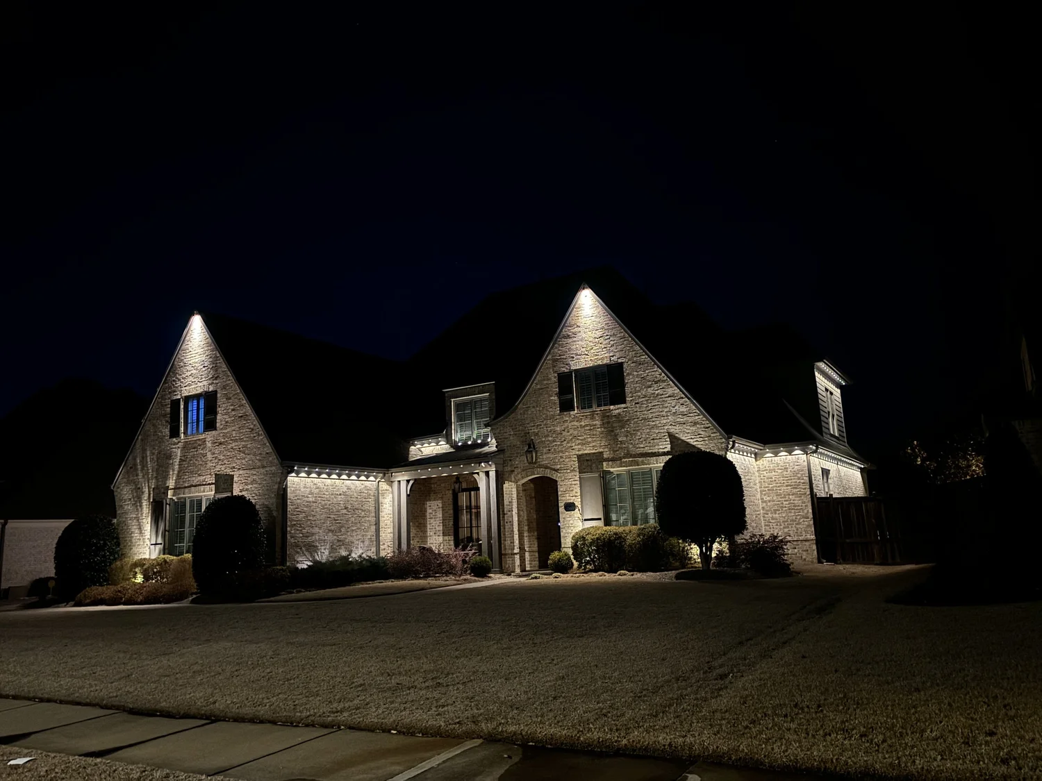 Permanent LED lighting glowing warm white along a home's peaks at night in Collierville