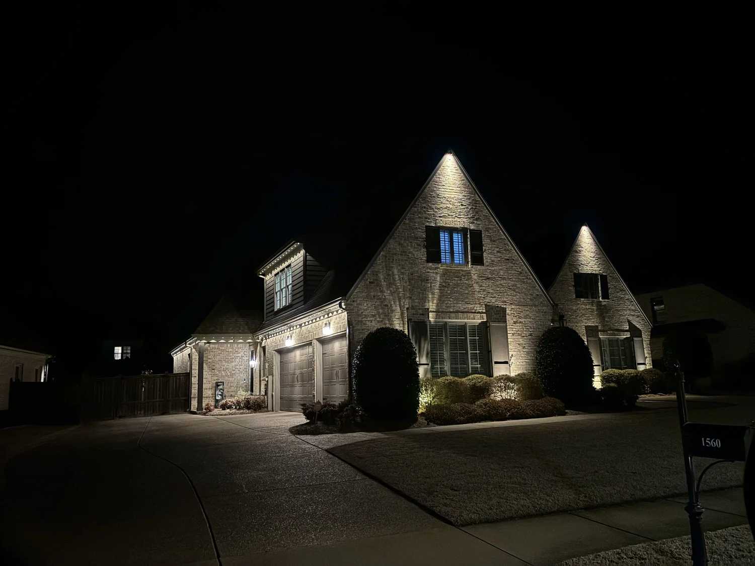 Two-story home with permanent smart LED roofline lighting lit at night