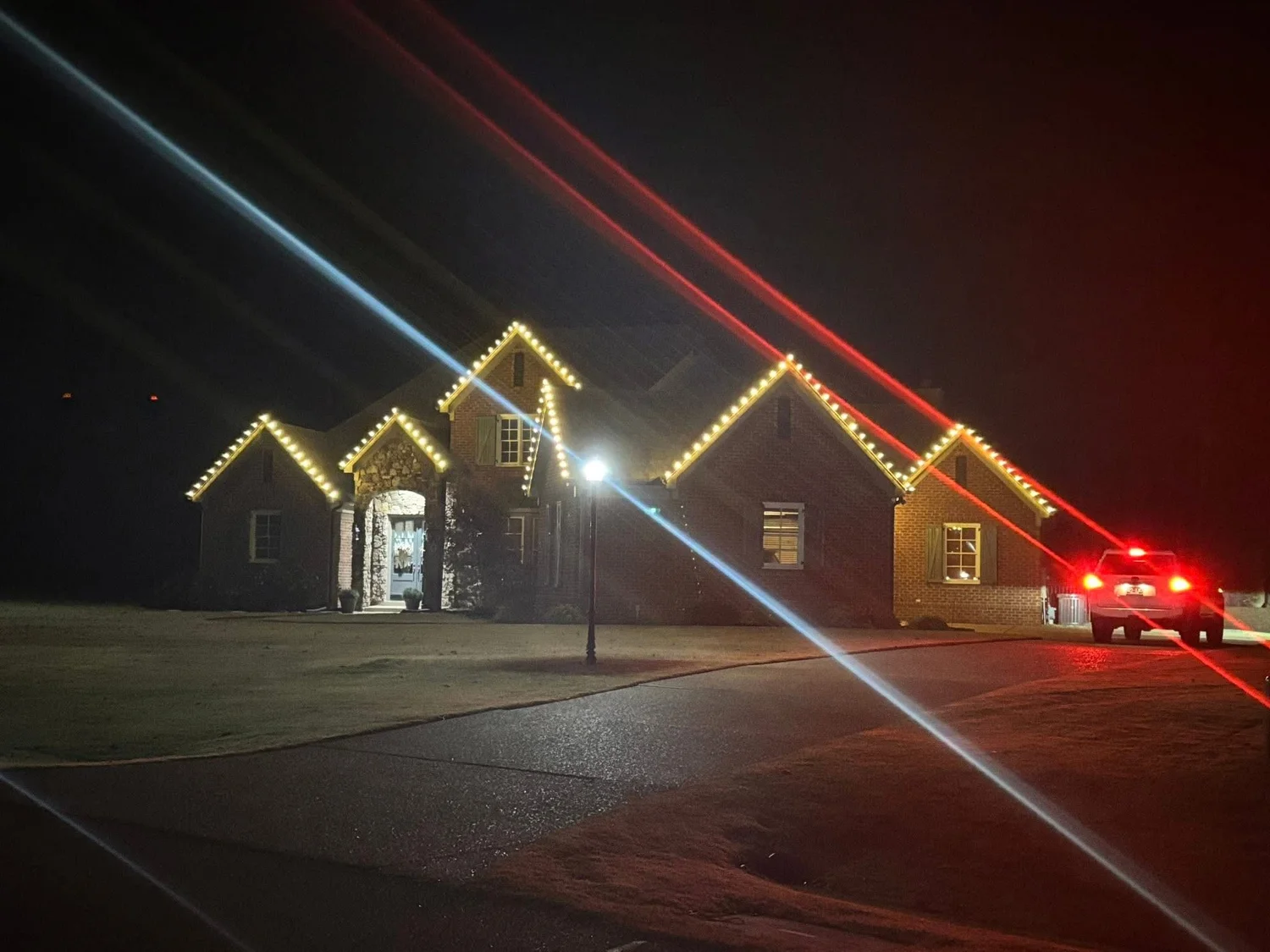 Brick home with lit peaks photographed from the street at night