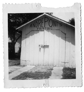 Black and white photo of a wooden building with a sign that reads 'Andre Pont's Printing' on the front.