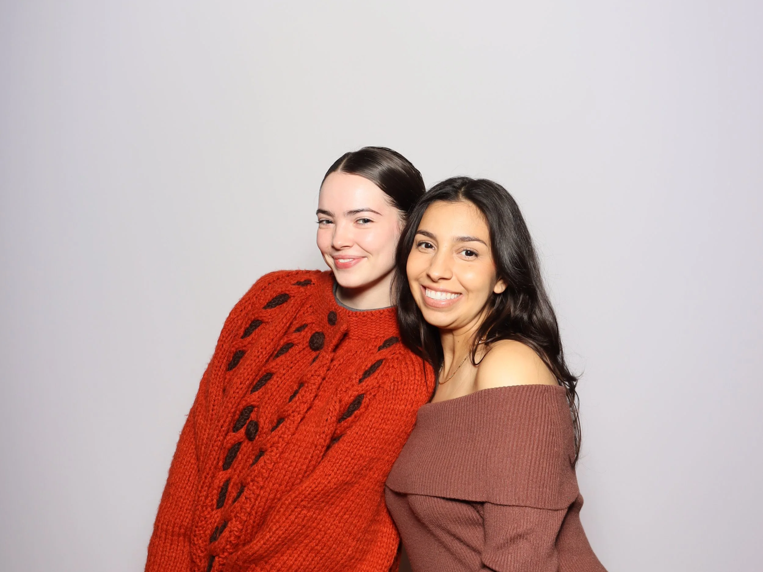 Two happy friends celebrating with a photobooth rental near me