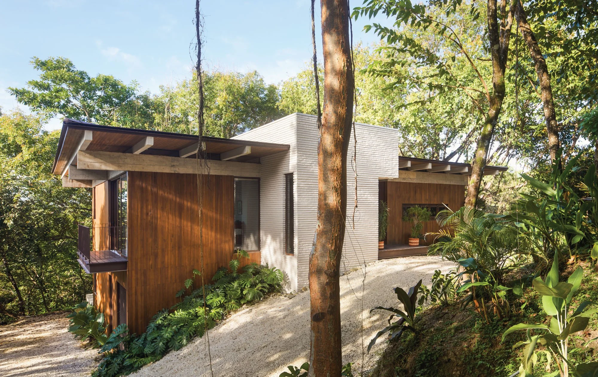 Tres Pochotes House by FAMM Arquitectura — brick and teak volumes set among the trees on a gravel drive, Playa Hermosa, Costa Rica