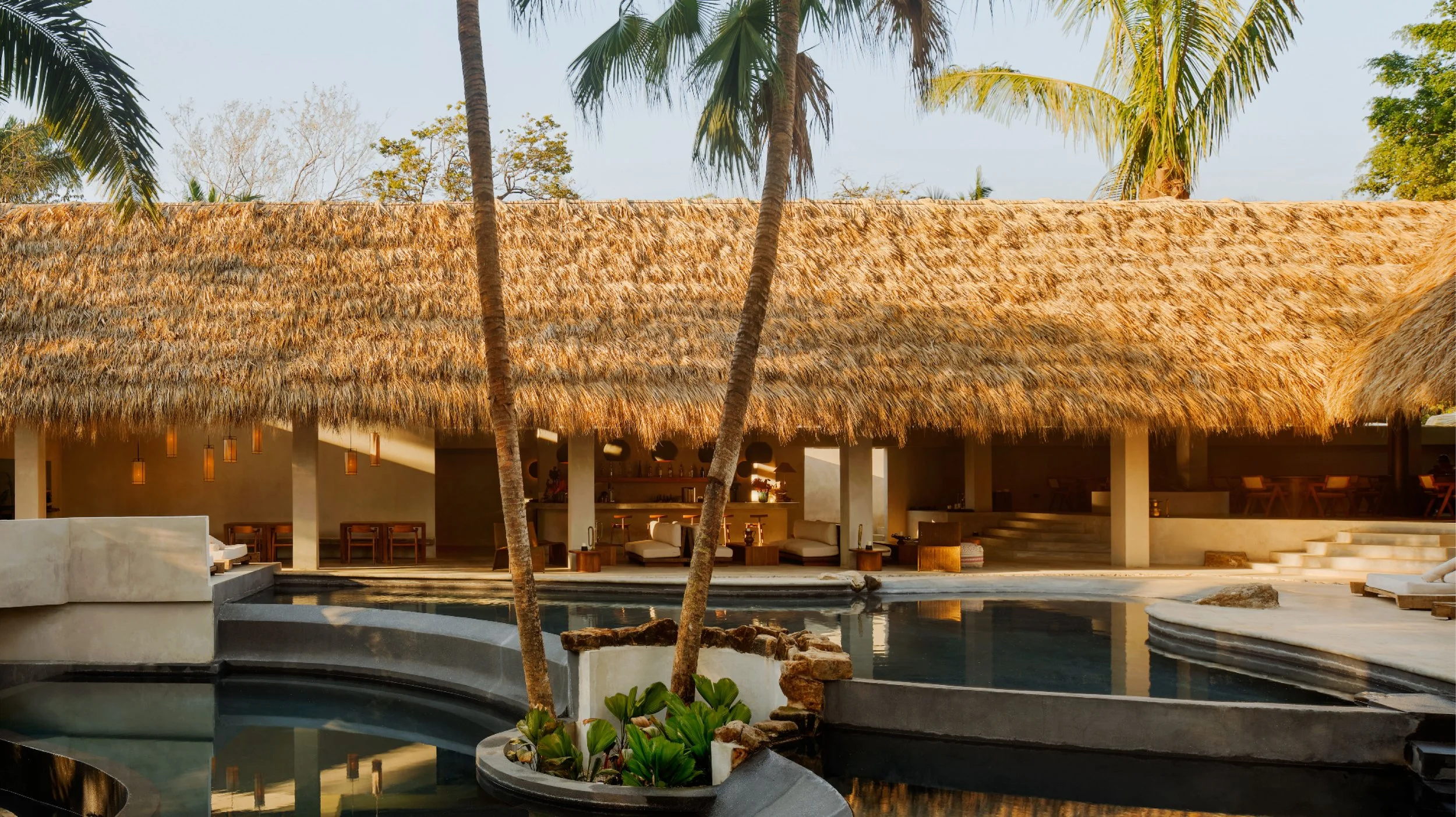 Hotel ESH thatched pavilion and pool in Huacas, Nosara, Costa Rica, with palm trees and concrete daybeds, by FAMM Arquitectura