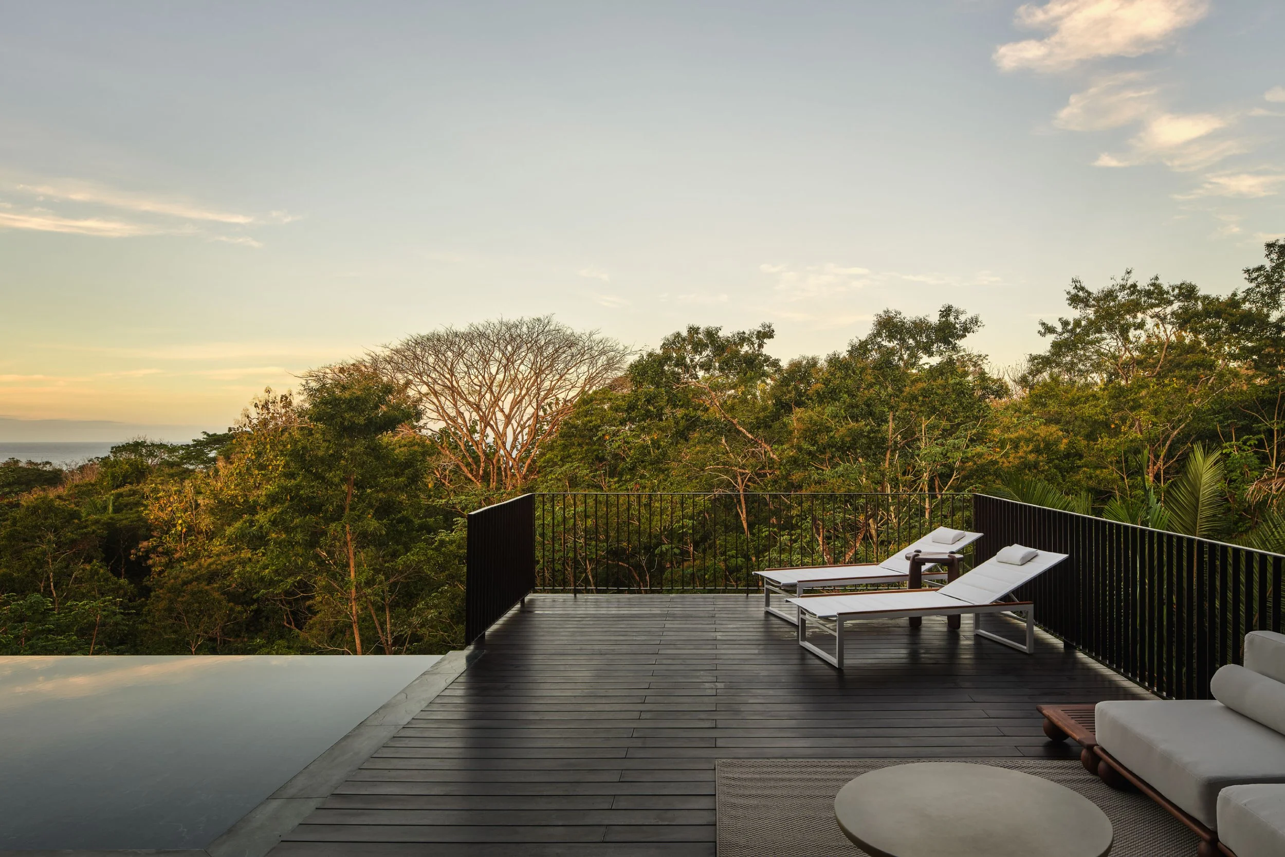 Minibauta House terrace at sunset in Santa Teresa, Costa Rica, with infinity pool edge and forest views, by FAMM Arquitectura