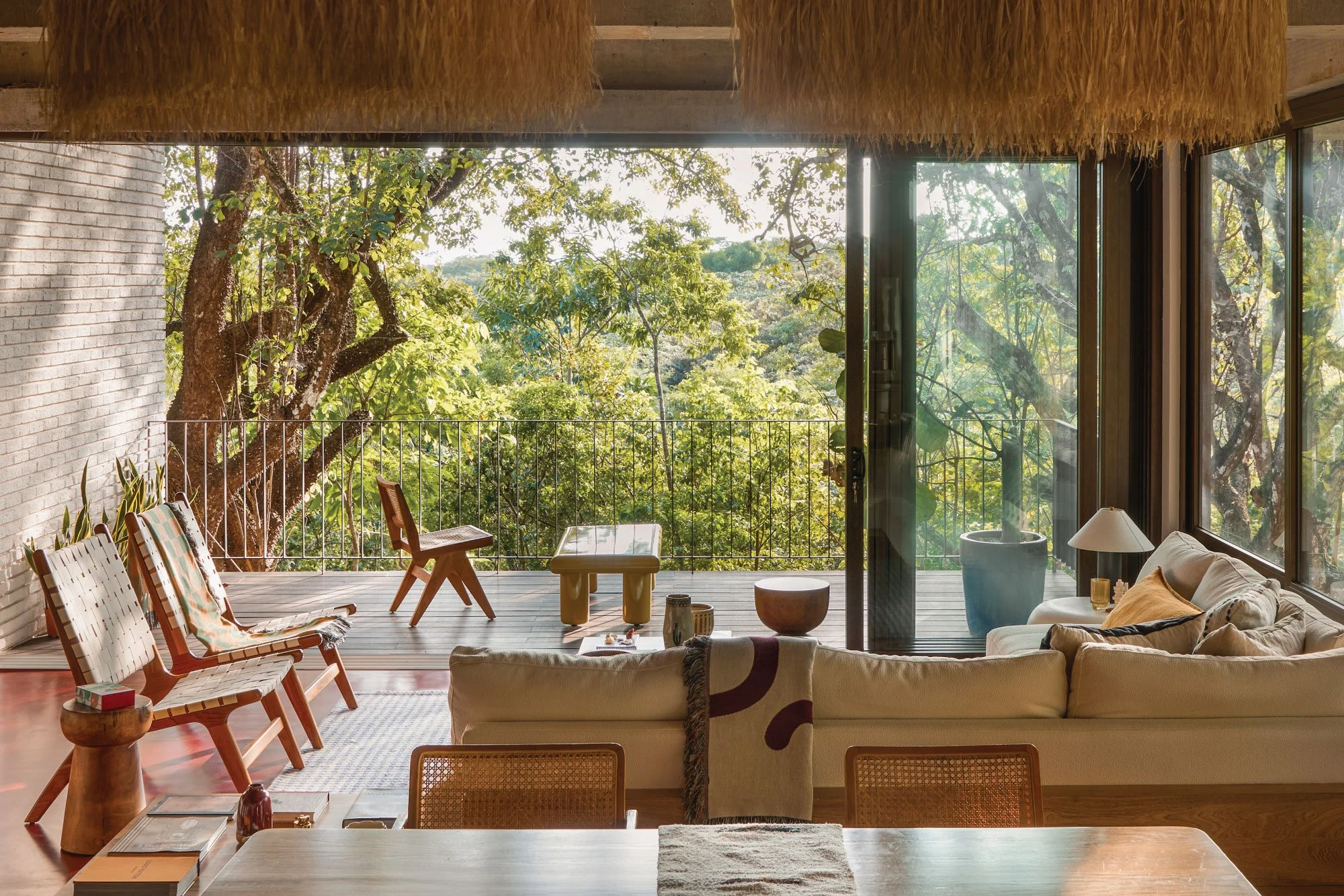 Tres Pochotes House living area by FAMM Arquitectura — open lounge with thatched ceiling opening onto a jungle-view deck, Costa Rica