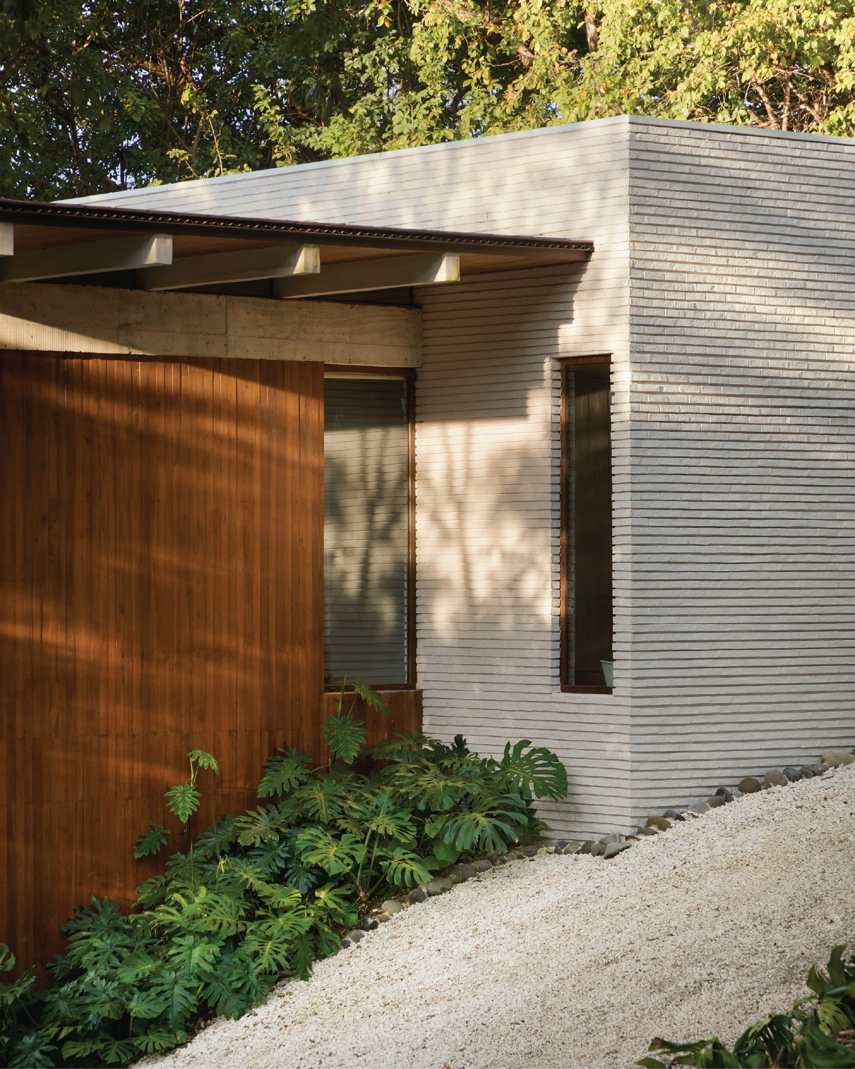 Tres Pochotes House by FAMM Arquitectura — brick and teak wood facade with tropical planting, Playa Hermosa, Costa Rica