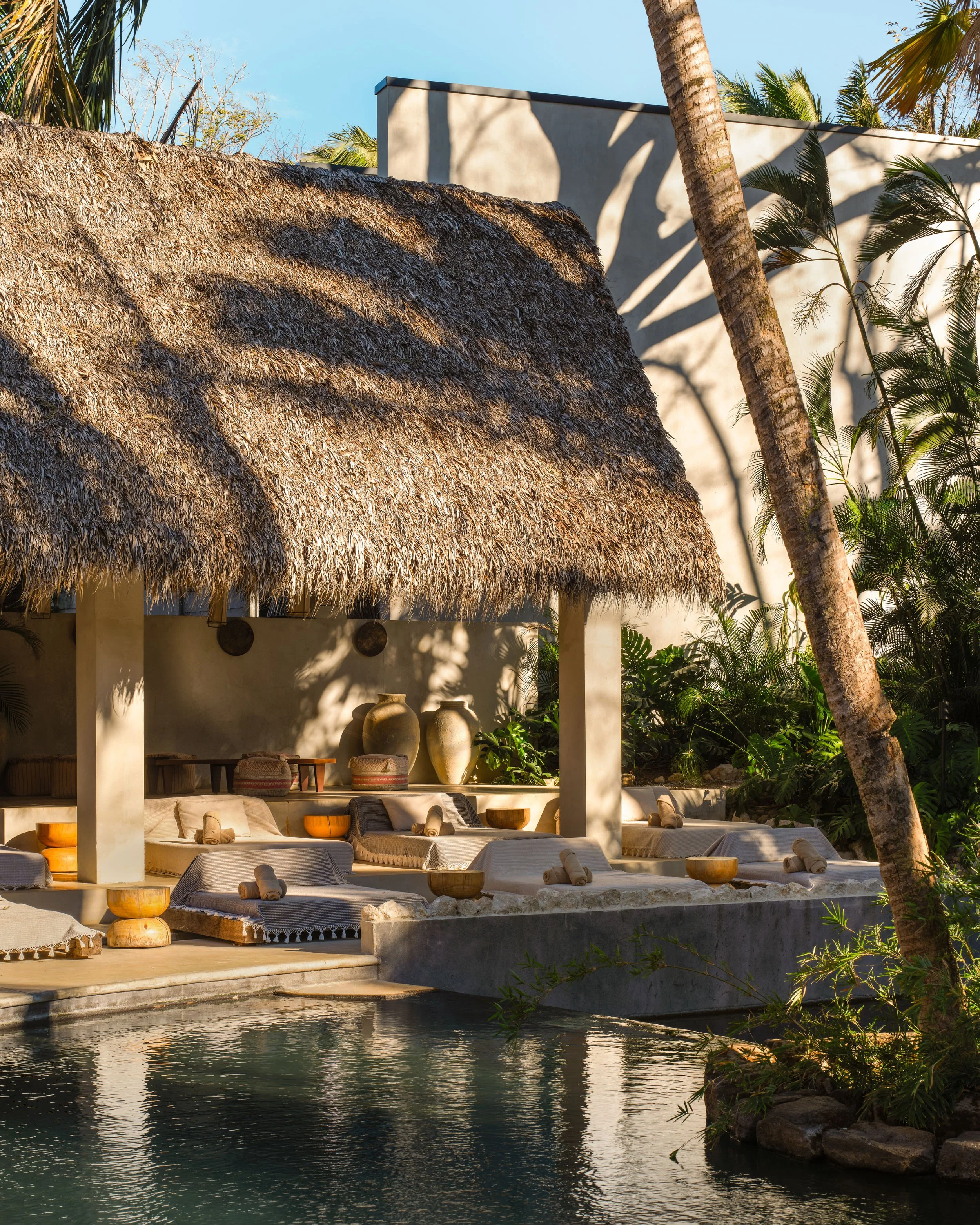 Hotel ESH pool platform in Huacas, Nosara, Costa Rica, with thatched pavilion, daybeds and water feature, by FAMM Arquitectura