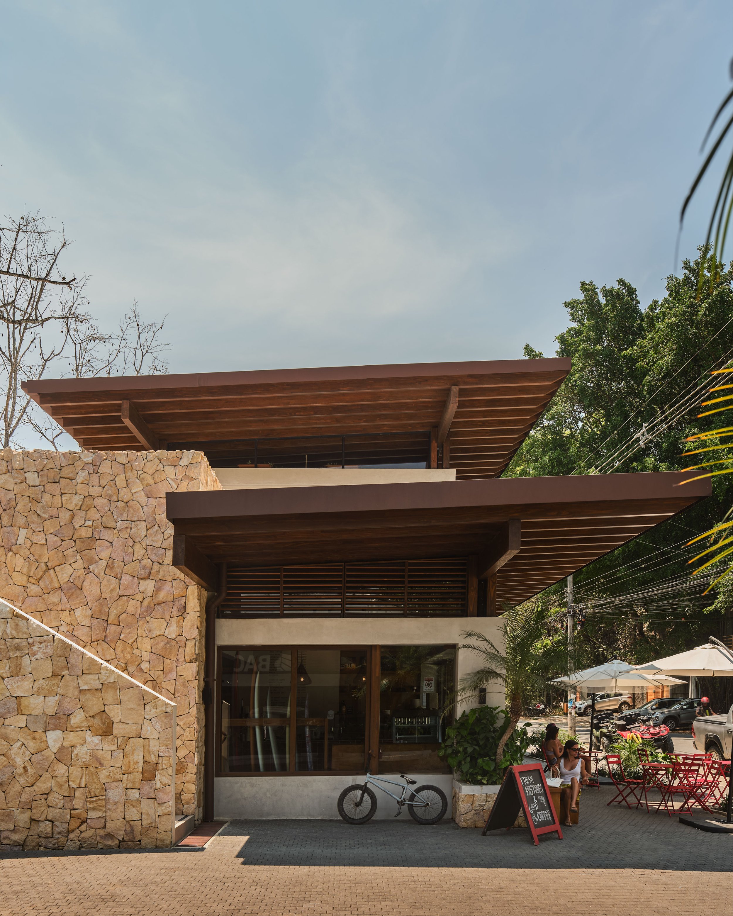 Plaza Pochote café terrace with stone wall and umbrellas in Santa Teresa, Costa Rica, by FAMM Arquitectura