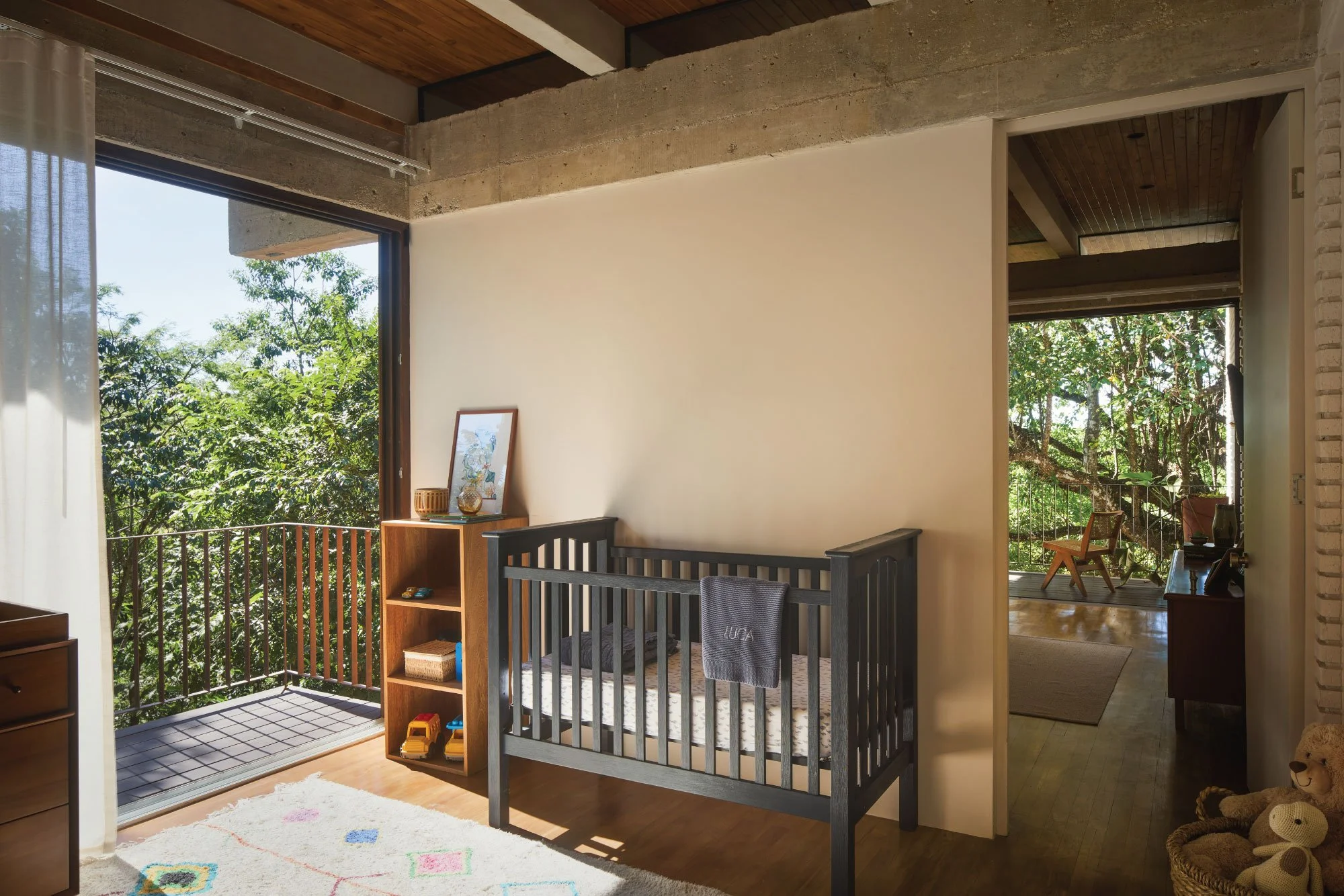 Tres Pochotes House nursery by FAMM Arquitectura — crib beside sliding doors opening to a treetop balcony, Playa Hermosa, Costa Rica