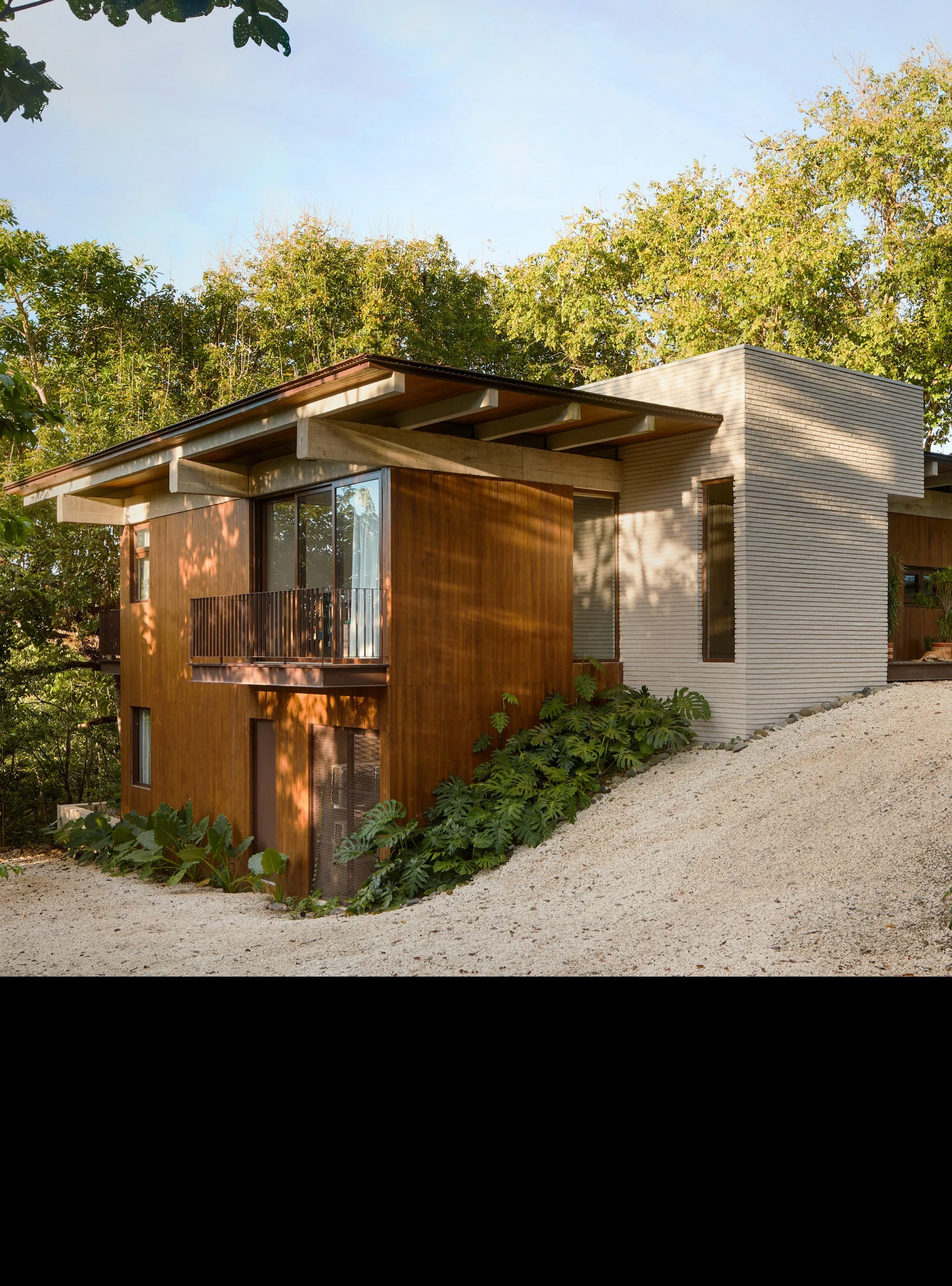 Tres Pochotes House by FAMM Arquitectura — brick and teak volumes set among the trees on a gravel drive, Playa Hermosa, Costa Rica