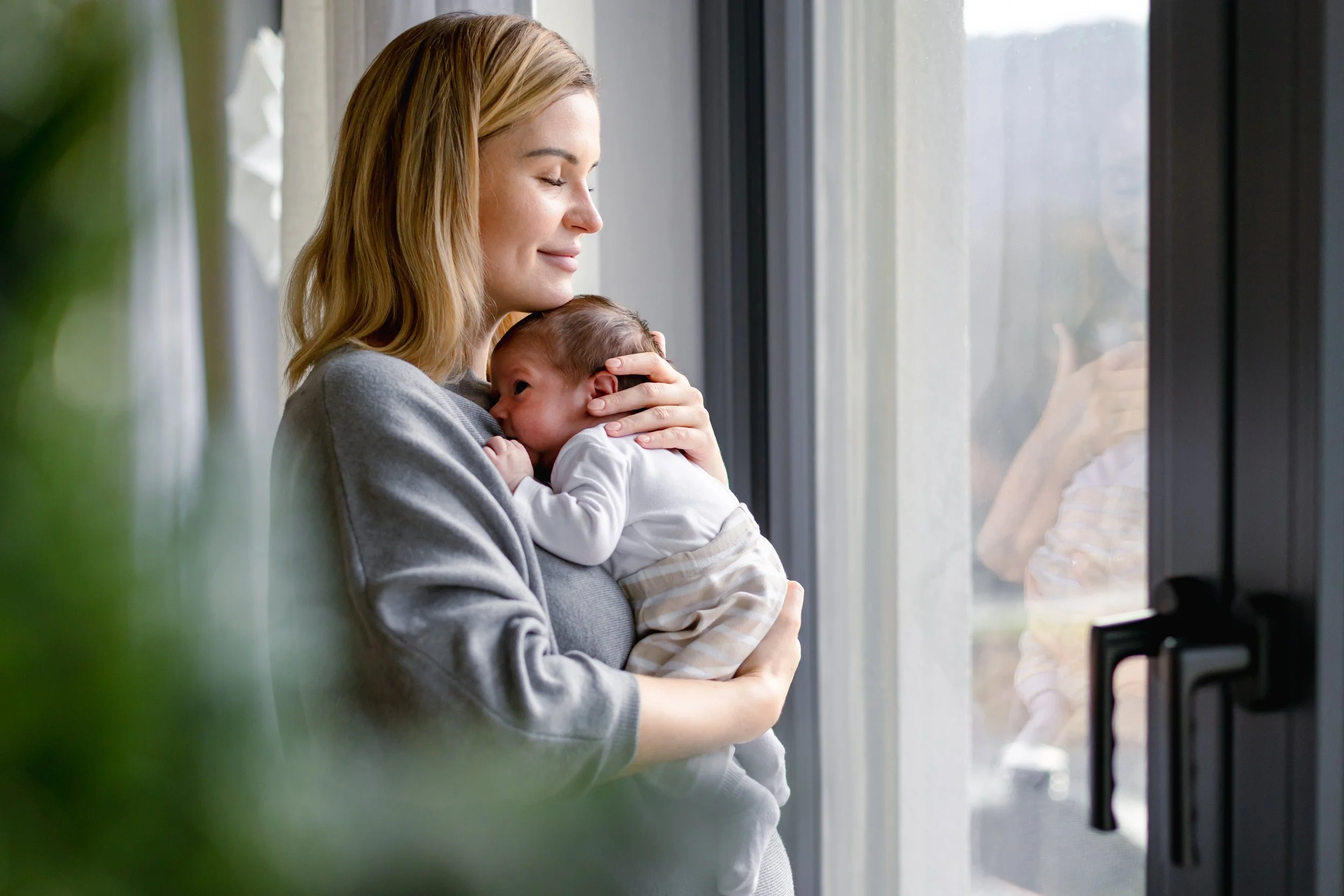 Mother holding her newborn during a calm postpartum moment, reflecting compassionate lactation and infant feeding support.