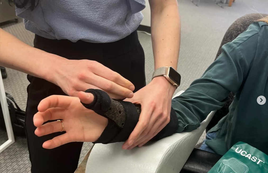 Medical professional applying a cast or splint to a person's hand with a finger injury.