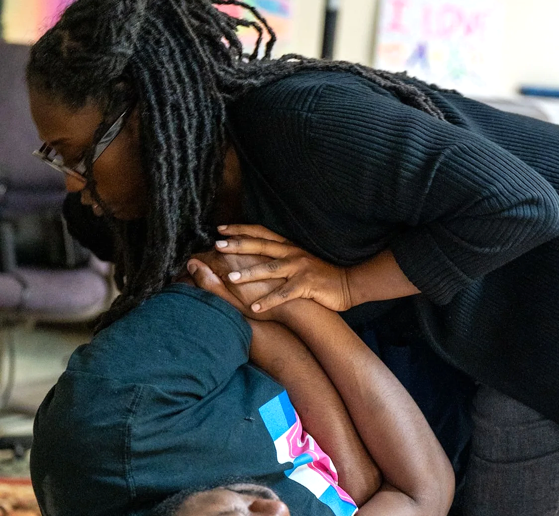 Dr. Magen Henry with glasses and dreadlocks leaning over adjusting a man.