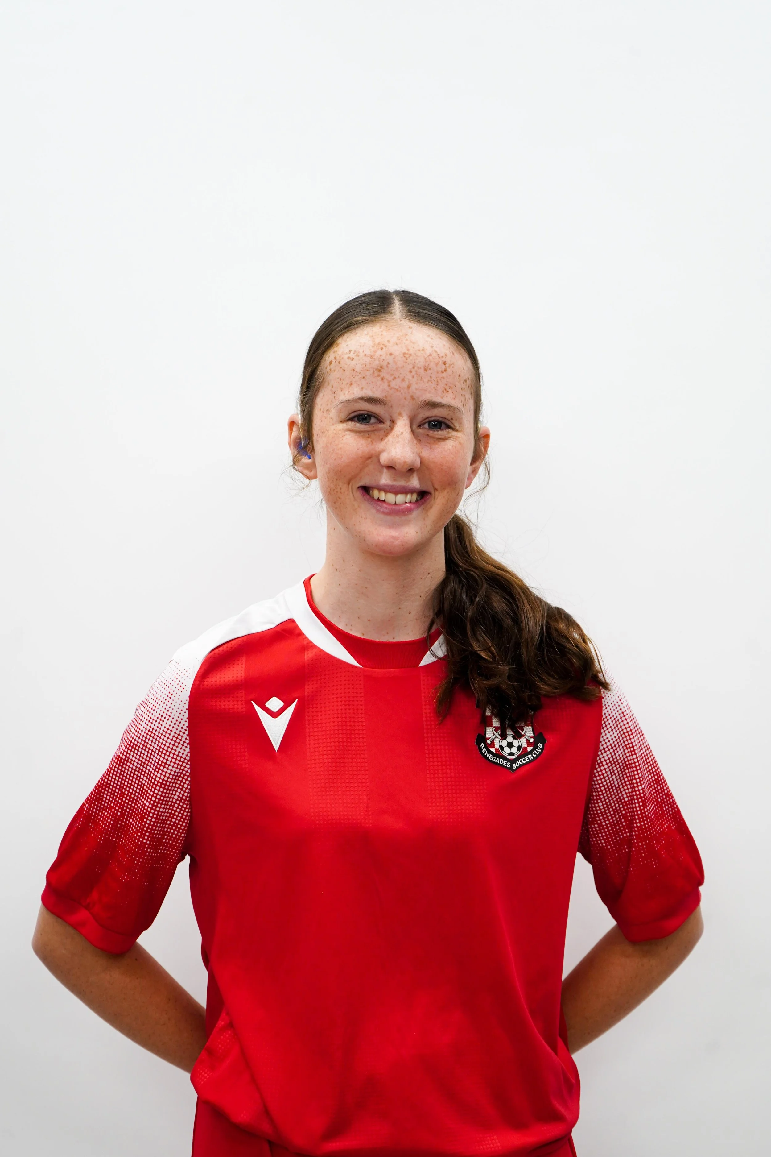A young woman in red sports jersey smiling in front of a white background.