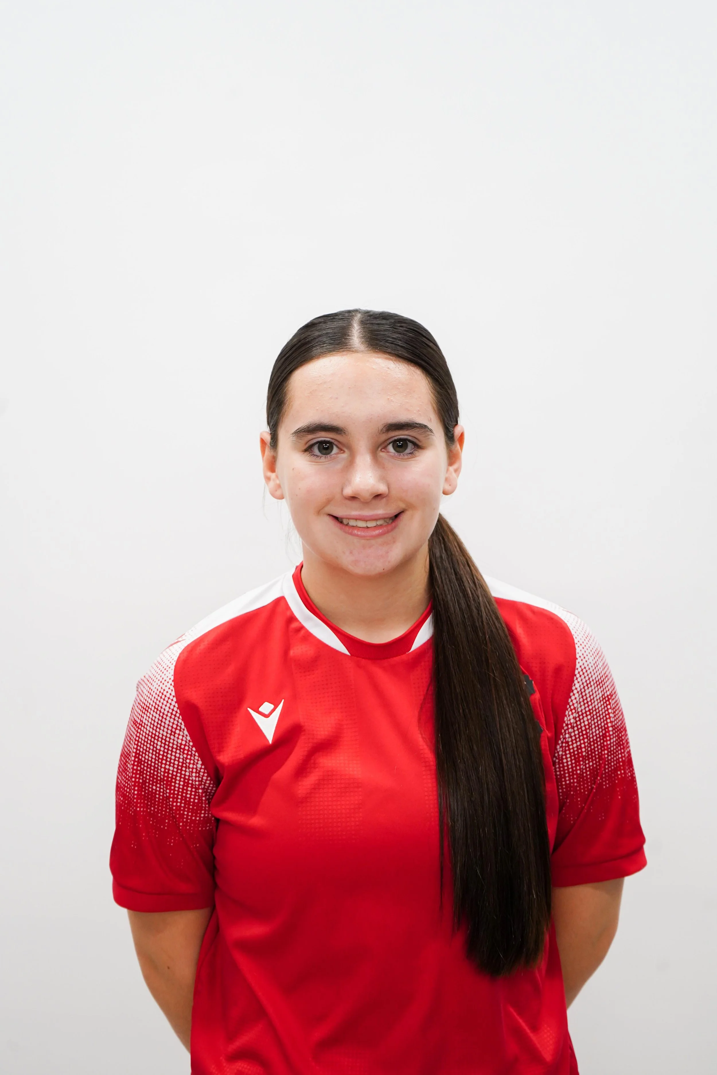 Young woman with long dark hair wearing a red sports jersey against a plain white background.