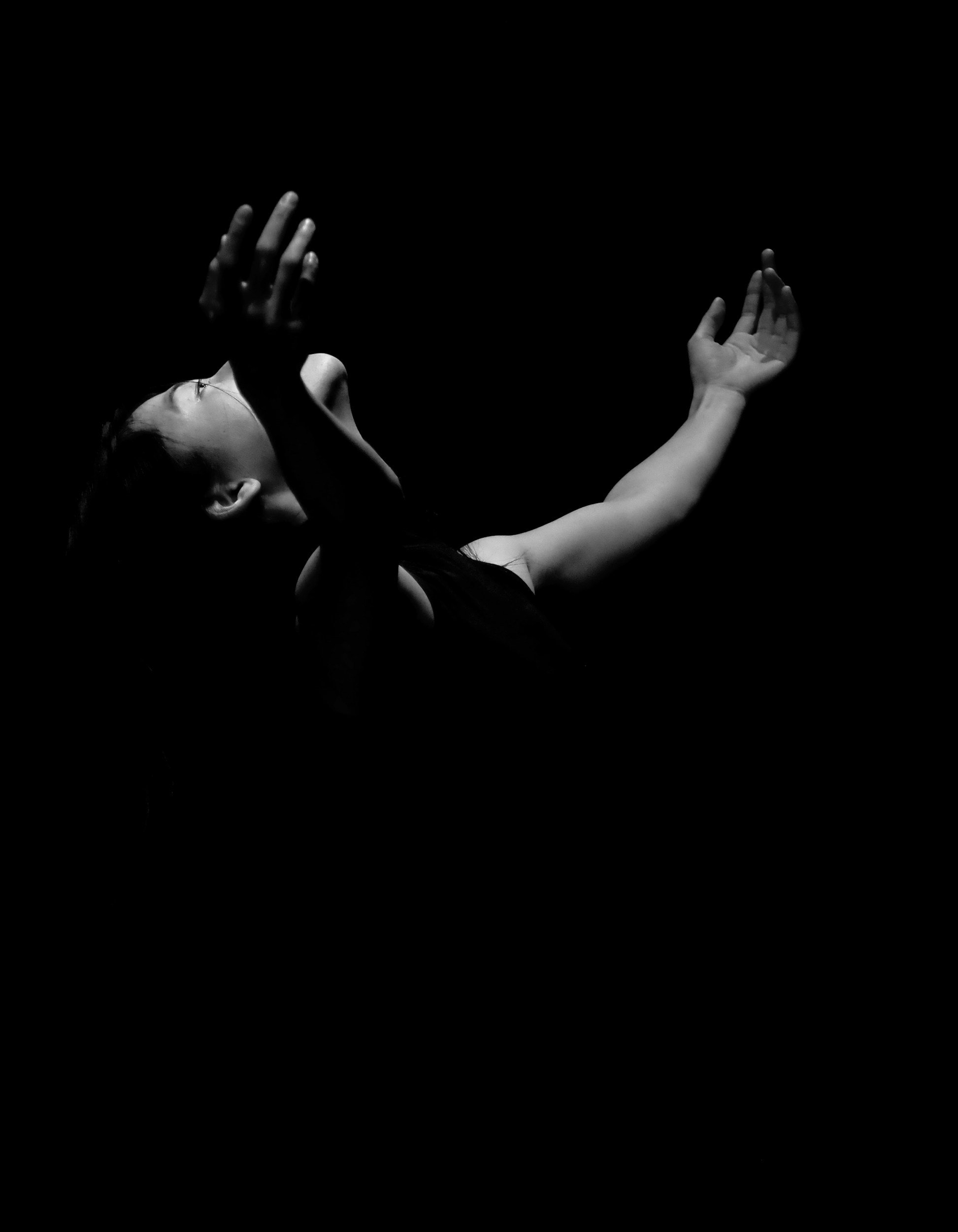 black and white photo of a dancer posed looking up with outstretched arms