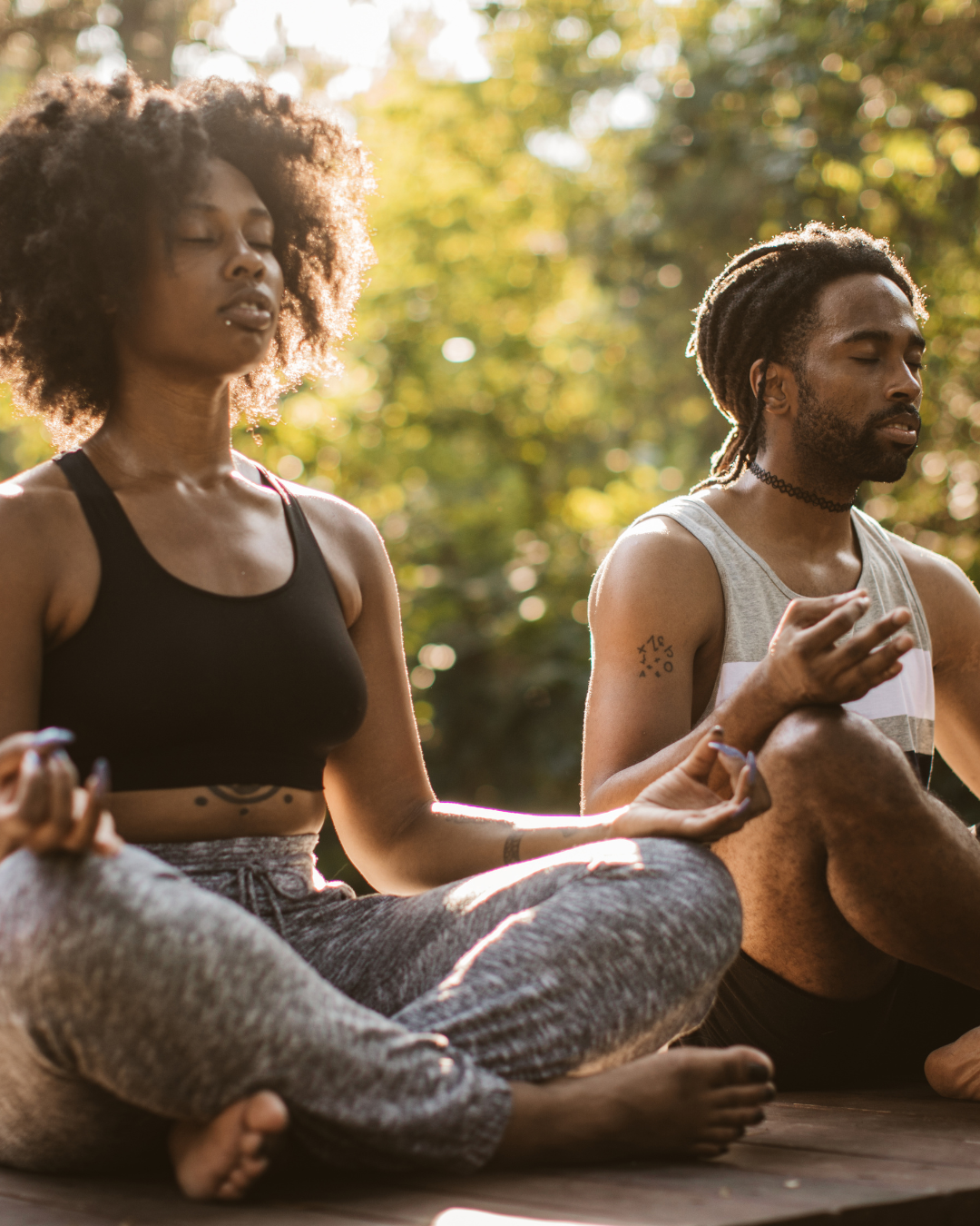 Two people sitting in meditation during yoga class outdoors