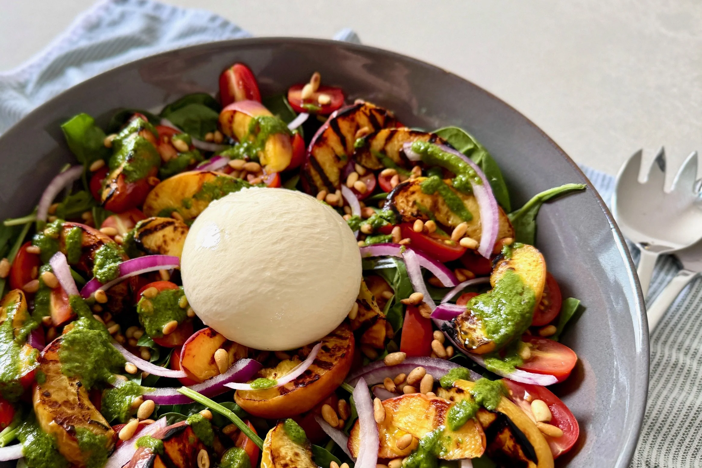 Grilled peach and tomato burrata salad with basil and pine nuts