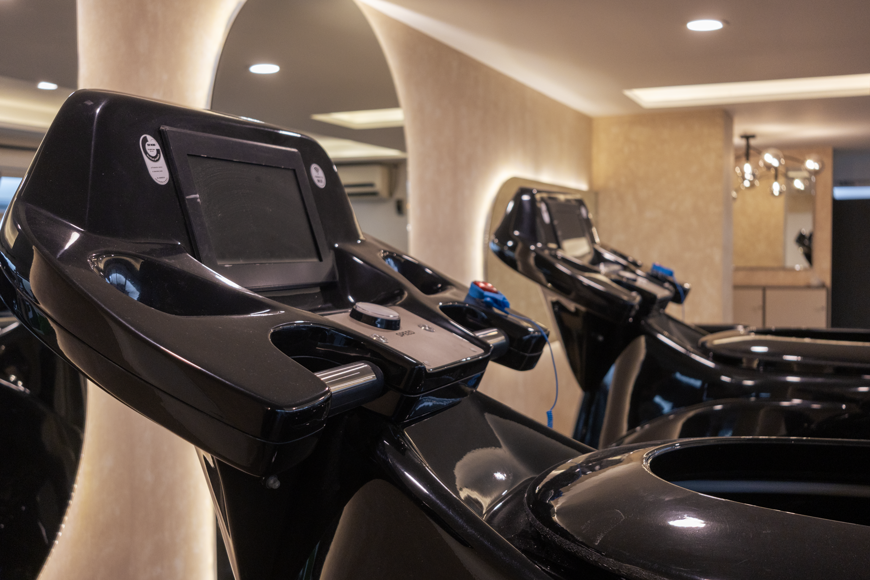 Scenic landscape of a large body of turquoise water surrounded by rolling green hills and tall mountains under a cloudy sky.