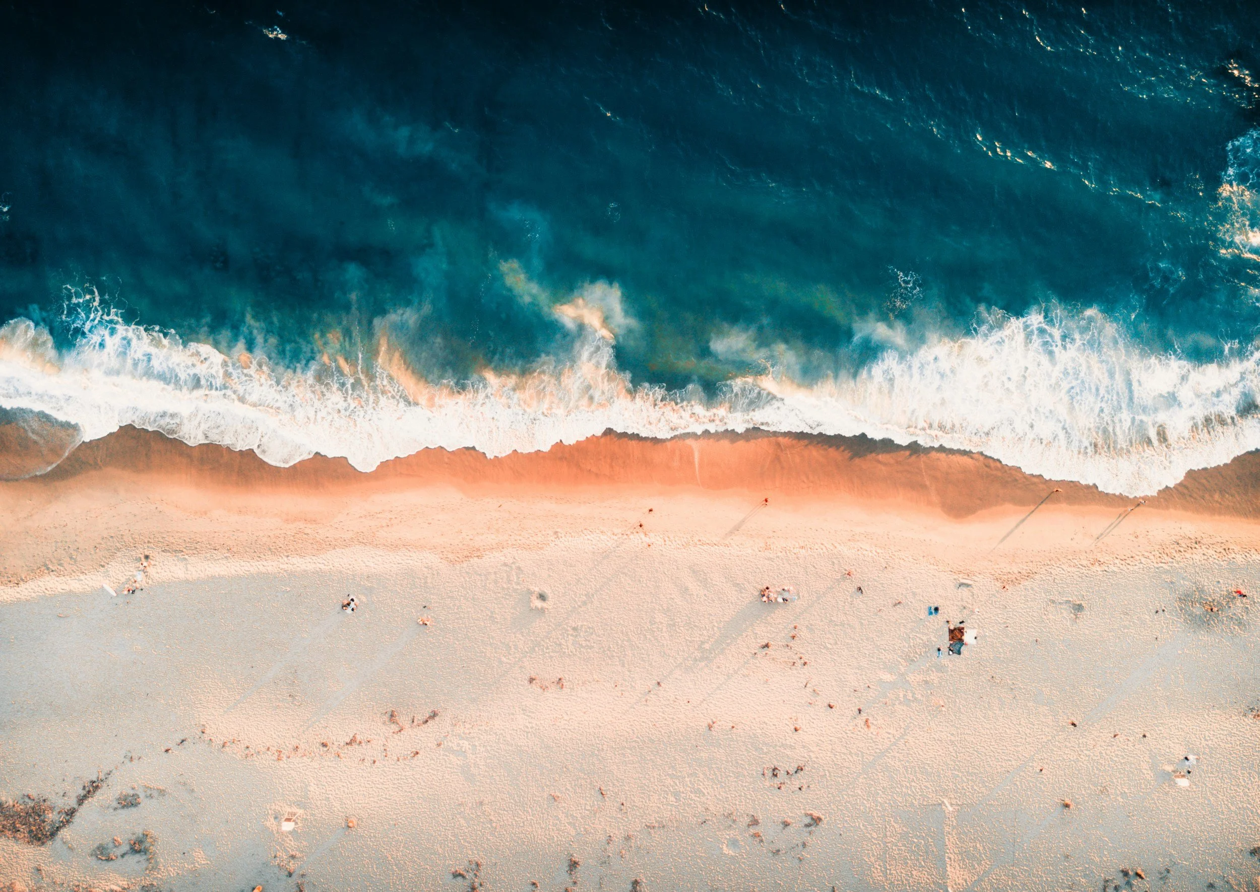 Aerial view of a sandy beach with ocean waves crashing onto the shore.