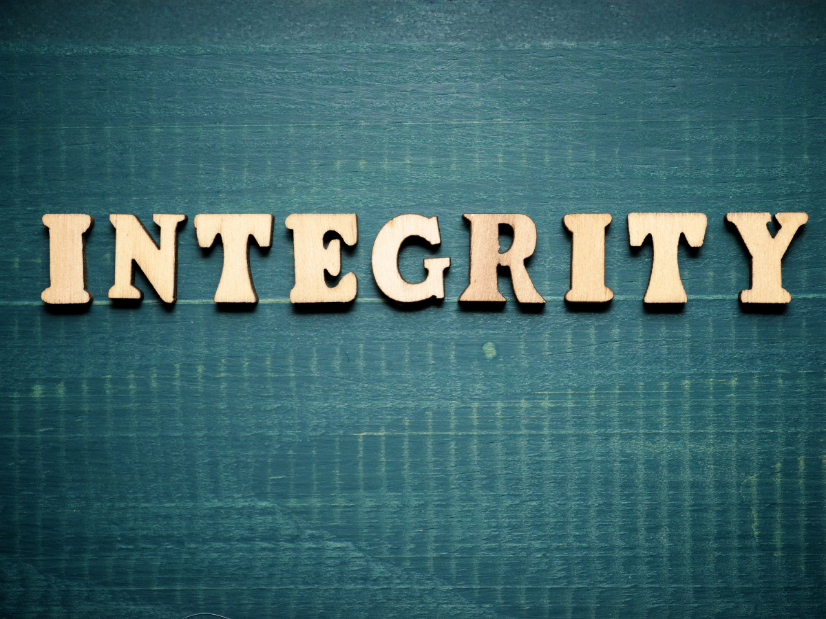Wooden letters spelling 'INTEGRITY' on a blue wooden surface.