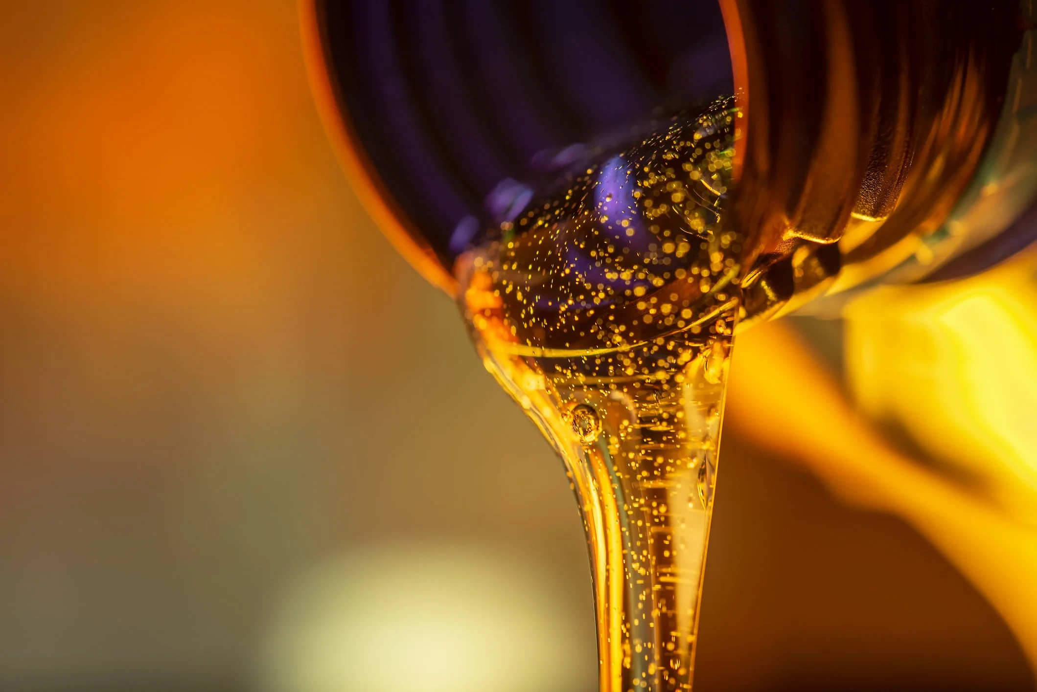 Close-up of a dark beer bottle pouring golden beer with bubbles into a glass.