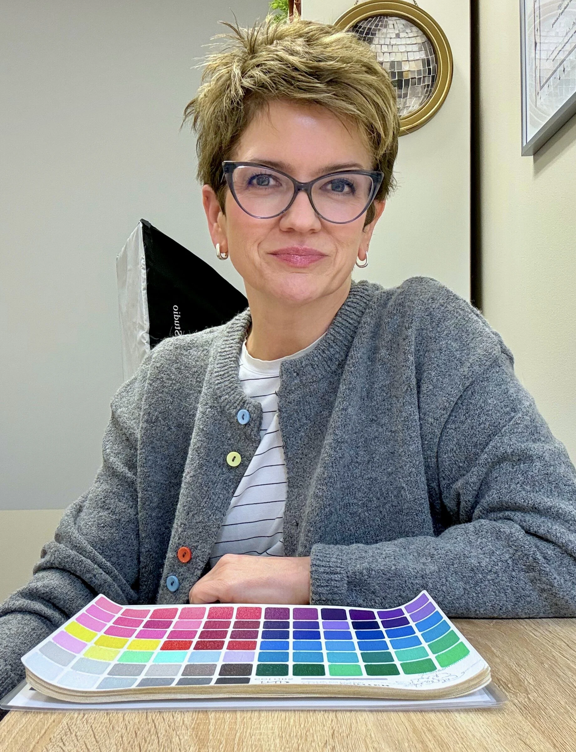 Liz, founder of The Color Edit, smiling in her color analysis studio with a seasonal color palette..