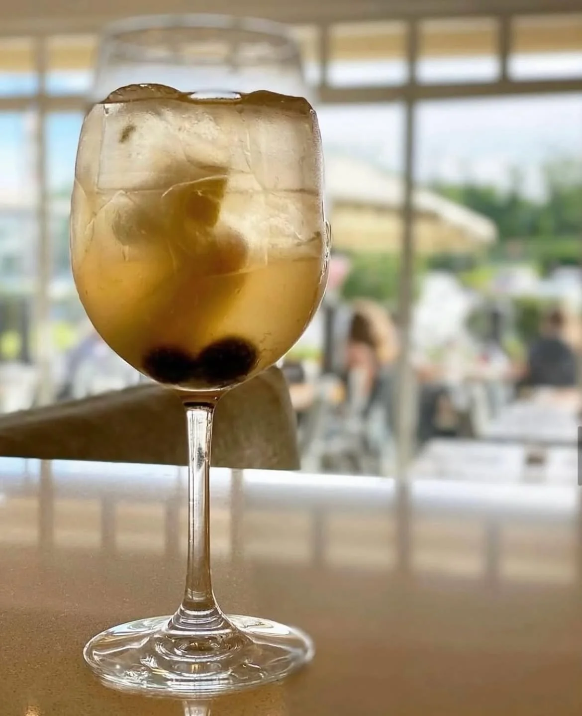 A glass of iced bubble tea with tapioca pearls on a table at a restaurant or cafe.