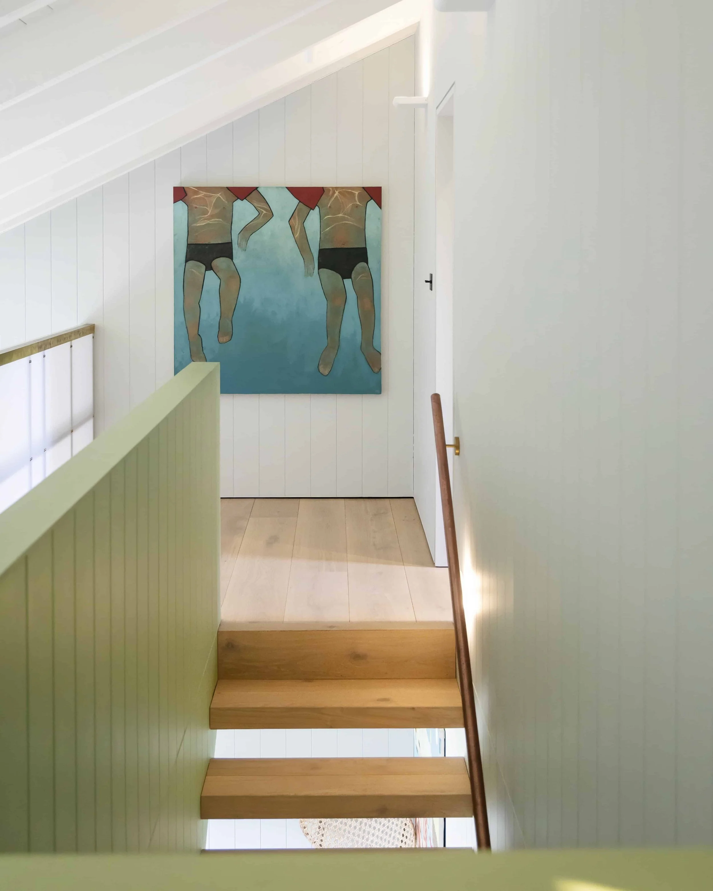 Interior view of a staircase landing with a painting of children swimming on the wall.