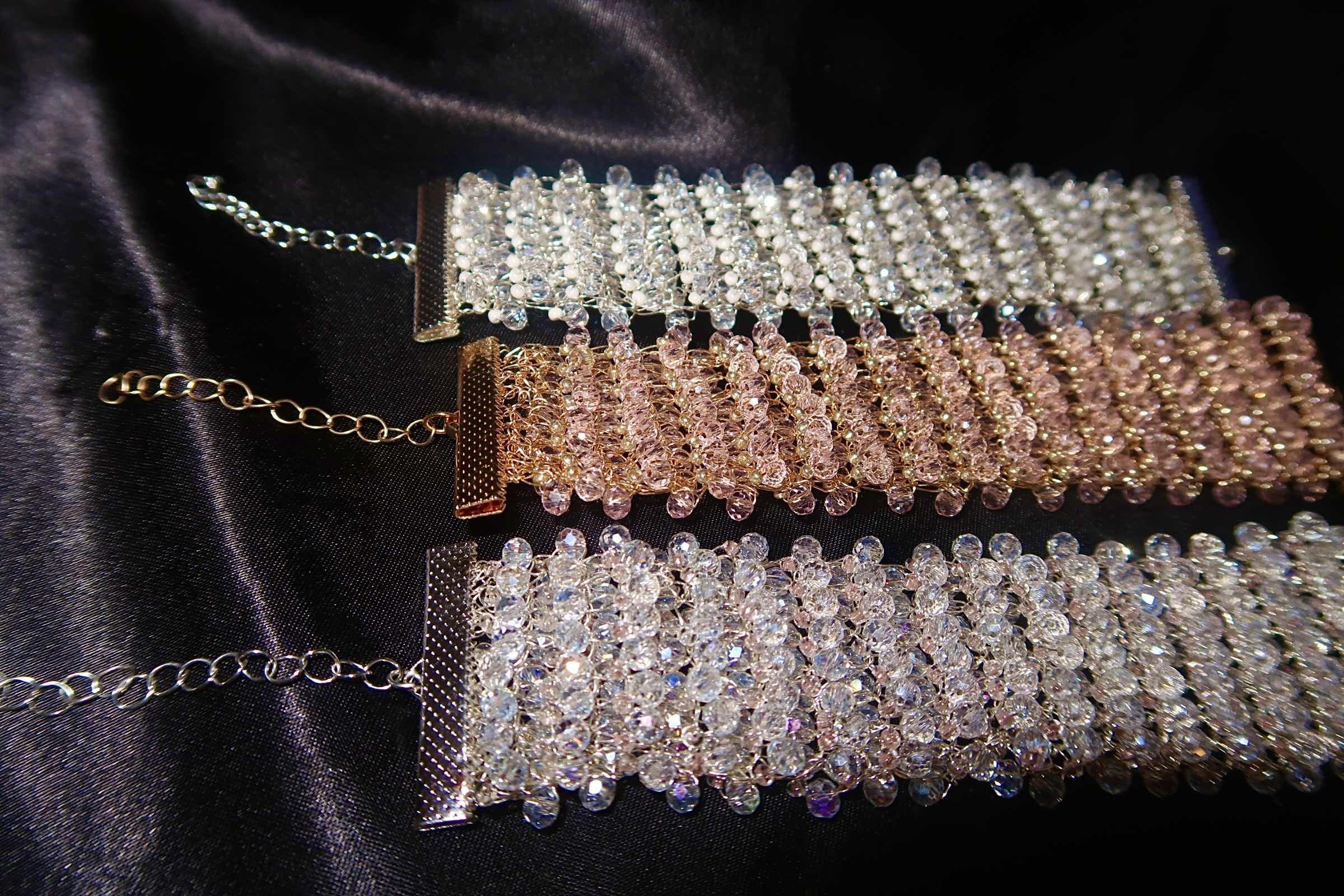 Three sparkling rhinestone bracelect with chain closures on a black satin fabric background.