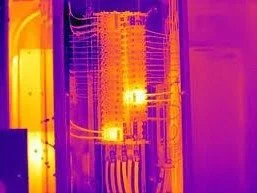 Infrared thermal image of an electronic circuit board with heat variations visible.