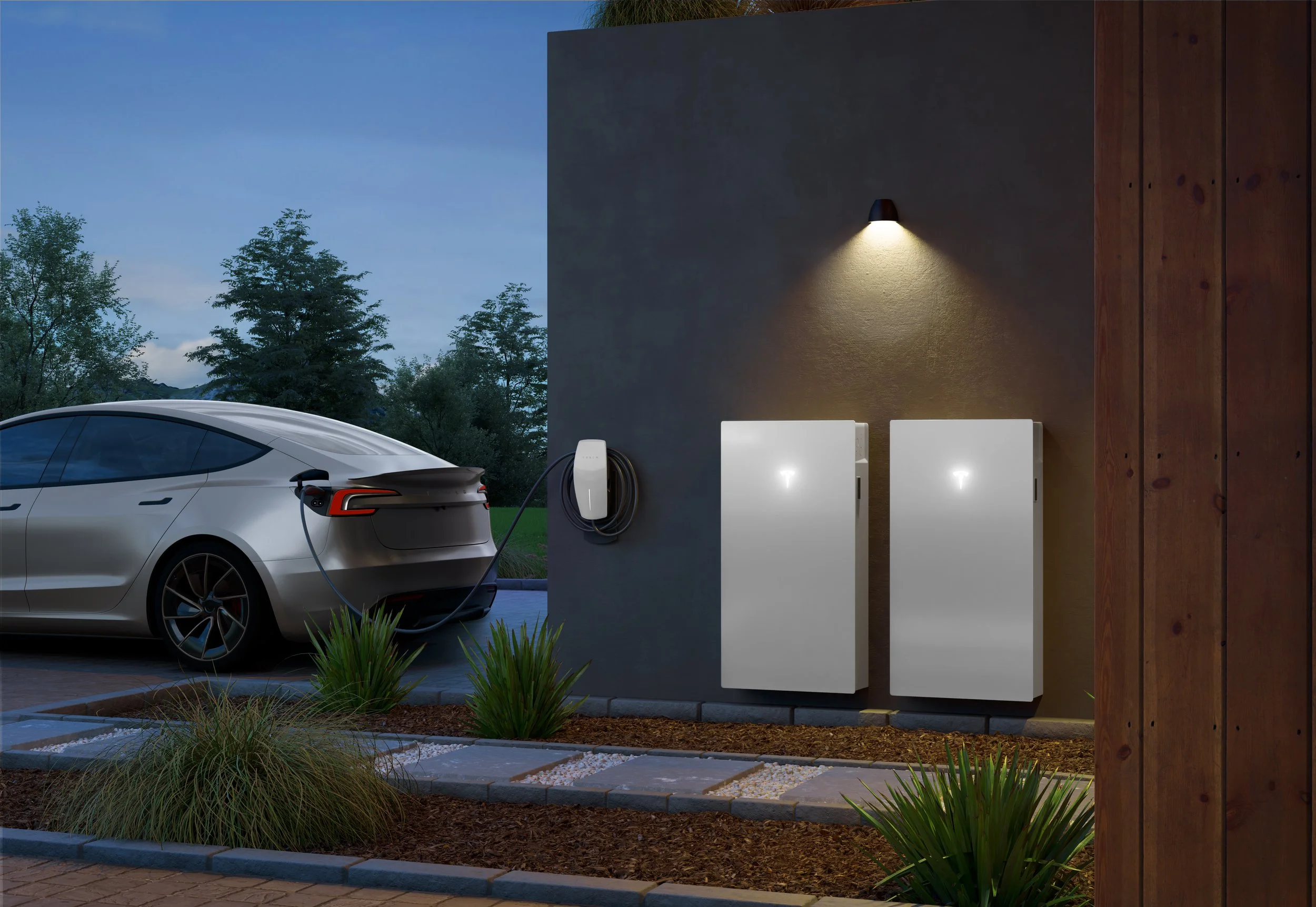 Electric vehicle charging station outdoors at dusk, with a white electric car plugged in, planted bushes, and modern exterior wall lighting.