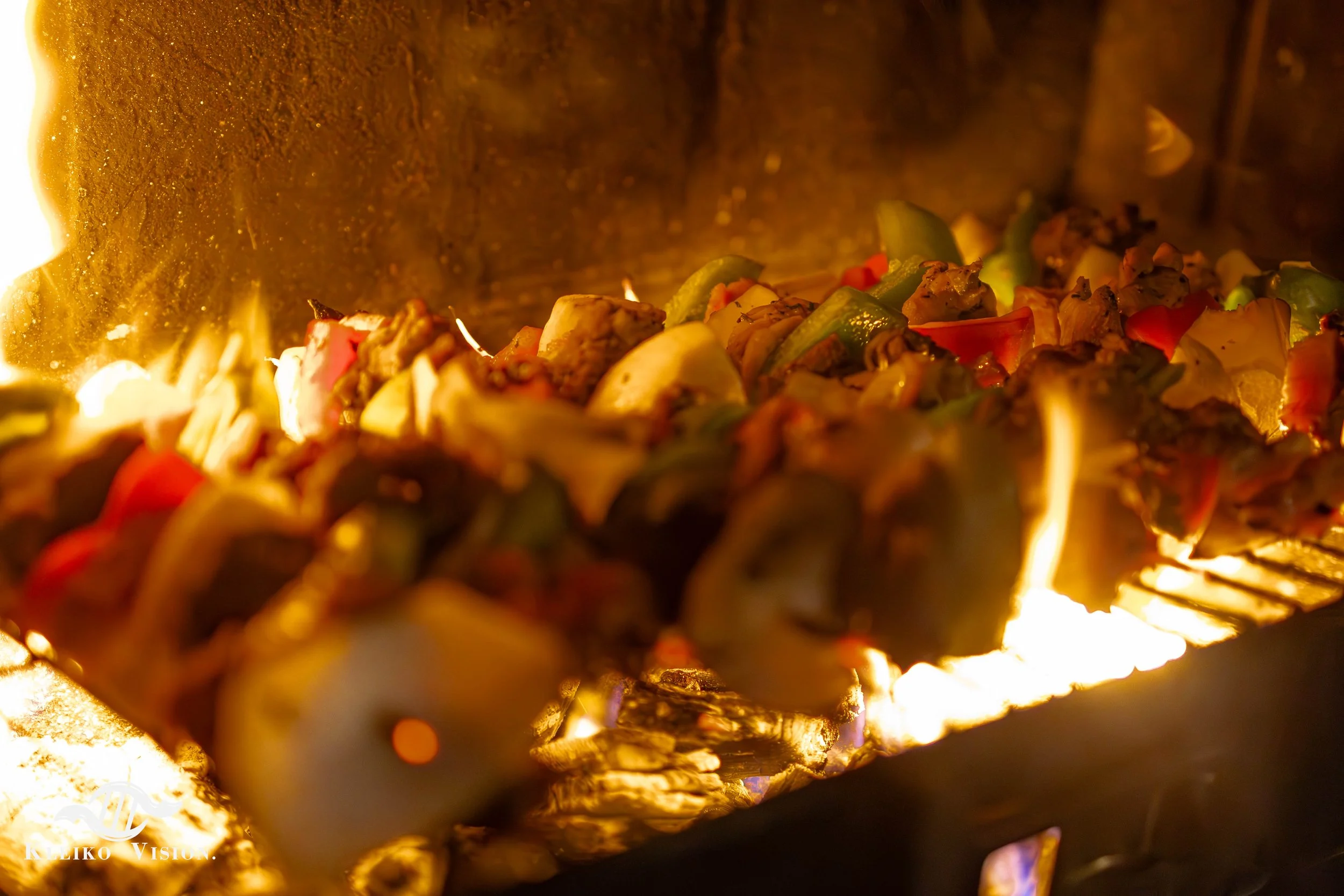 Chicken and vegetable skewers grilling over an open flame