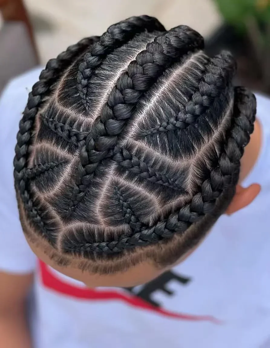 Top view of a child's head with intricate braided hairstyle featuring multiple geometric patterns and cornrows.