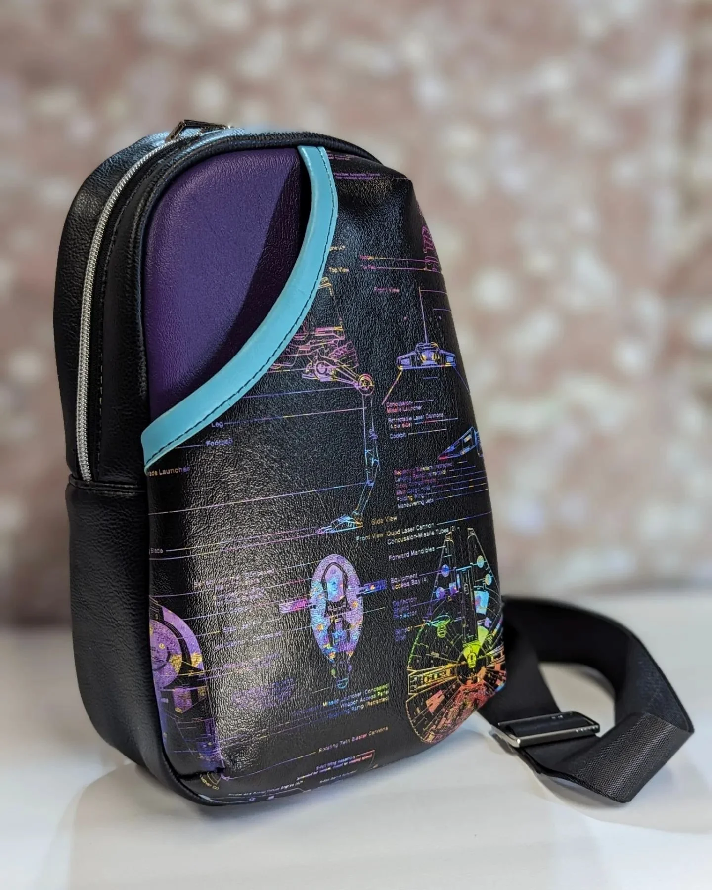 A black backpack with a futuristic, sci-fi style design featuring neon-colored technical diagrams and schematics, including vehicle outlines and mechanical details.