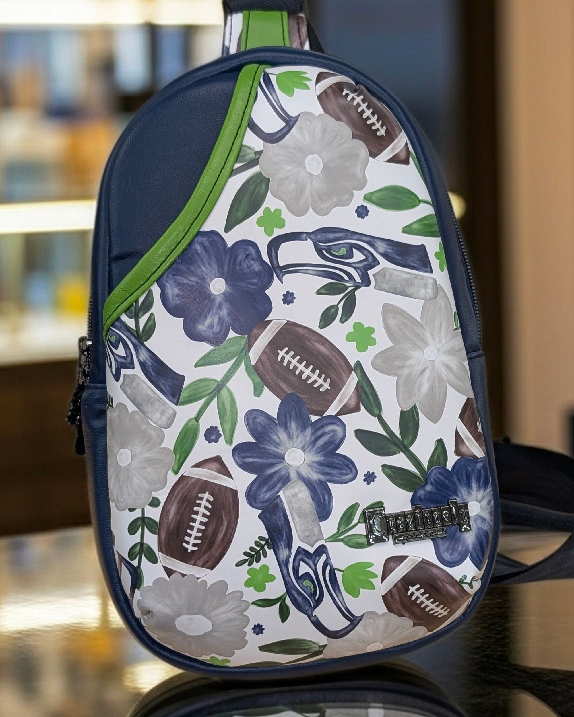 Handmade "Rumor" crossbody bag with blue vinyl and a Seahawks theme on the front, crafted by Creatively Speaking Designs.