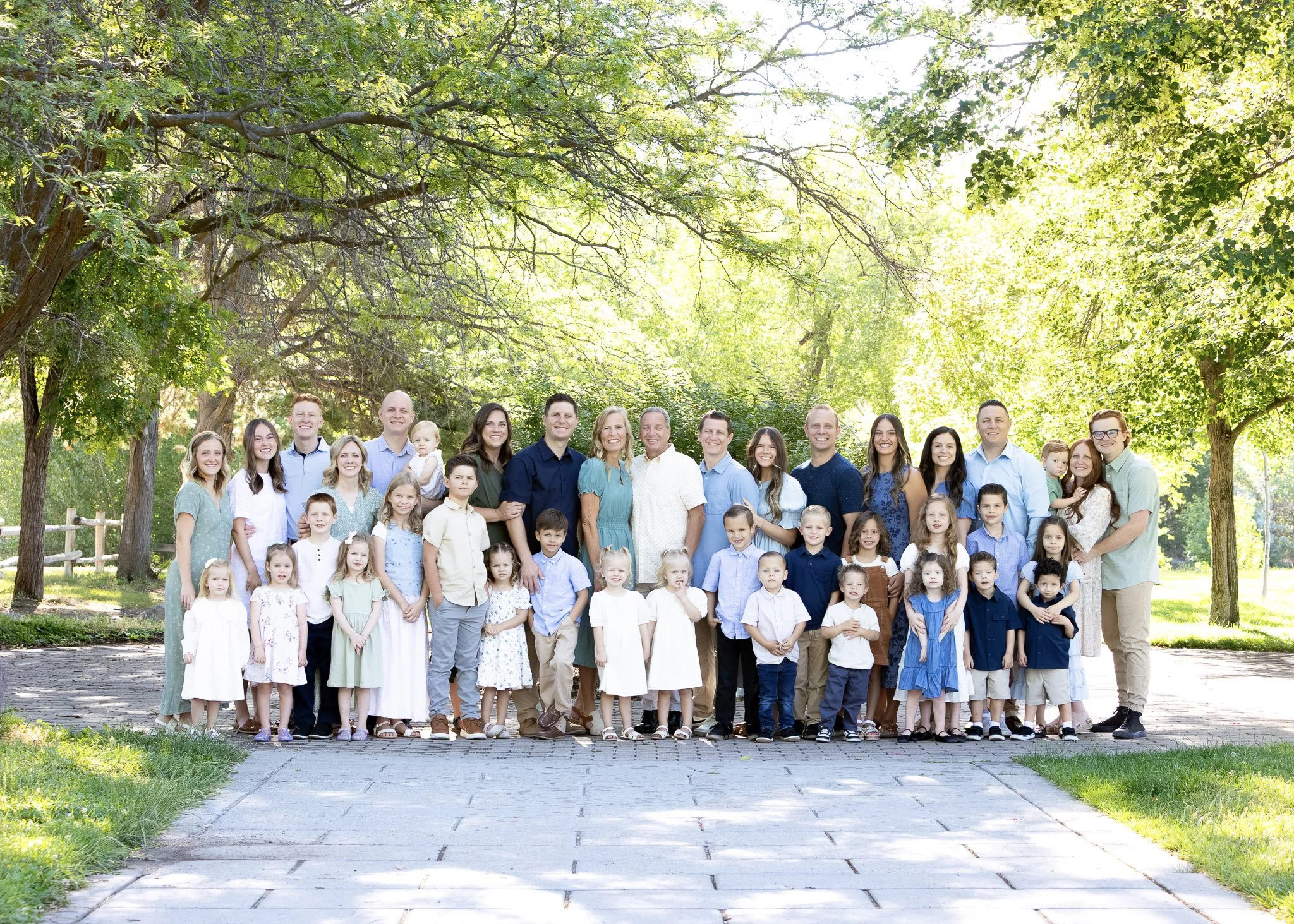 Group photo of wedding family and friends outdoors, with mountains and trees in the background, taken during sunset.